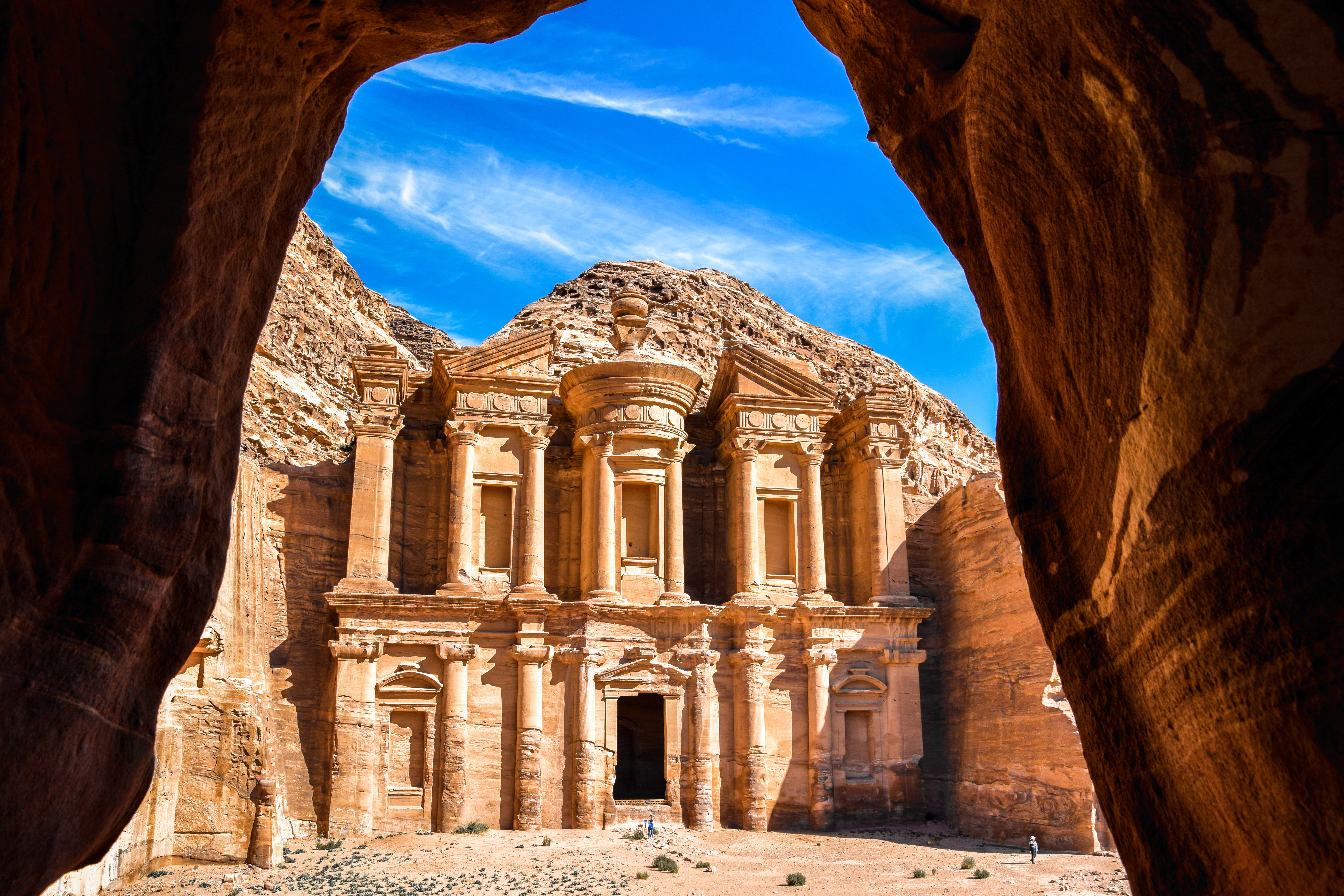 Fascinerende perspektiv gennem en hule mod Ad Deir klosteret i Petra, Jordan - et af verdens mest ikoniske historiske monumenter