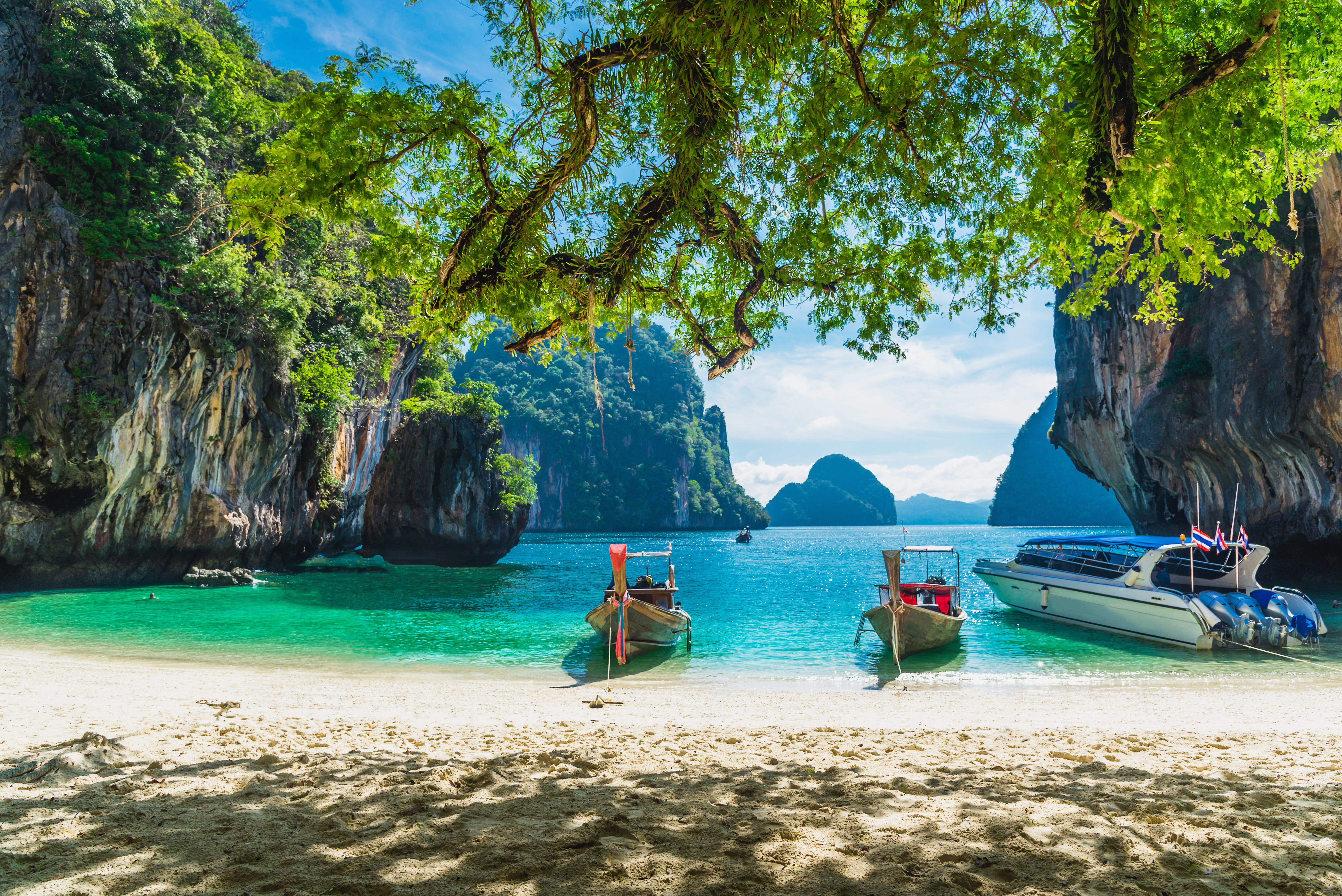 Smuk tropisk strandudflugt med longtail-baade i turkist vand ved Koh Lao Lading, Krabi i Thailand, med dramatiske kalkstensklipper og froedige tropiske traeer