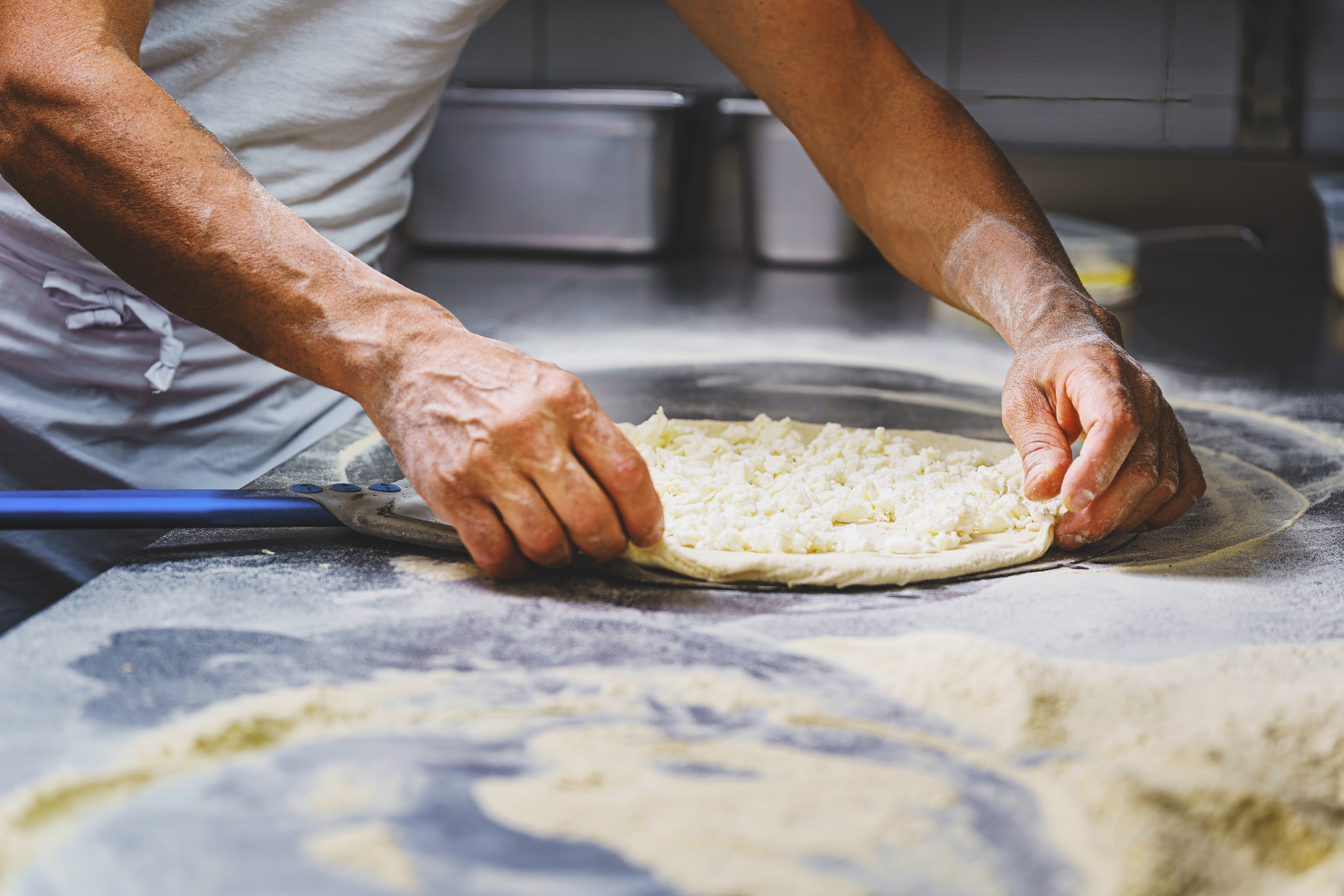 Autentisk italiensk pizzabager former traditionel napolitansk pizzadej med hænderne