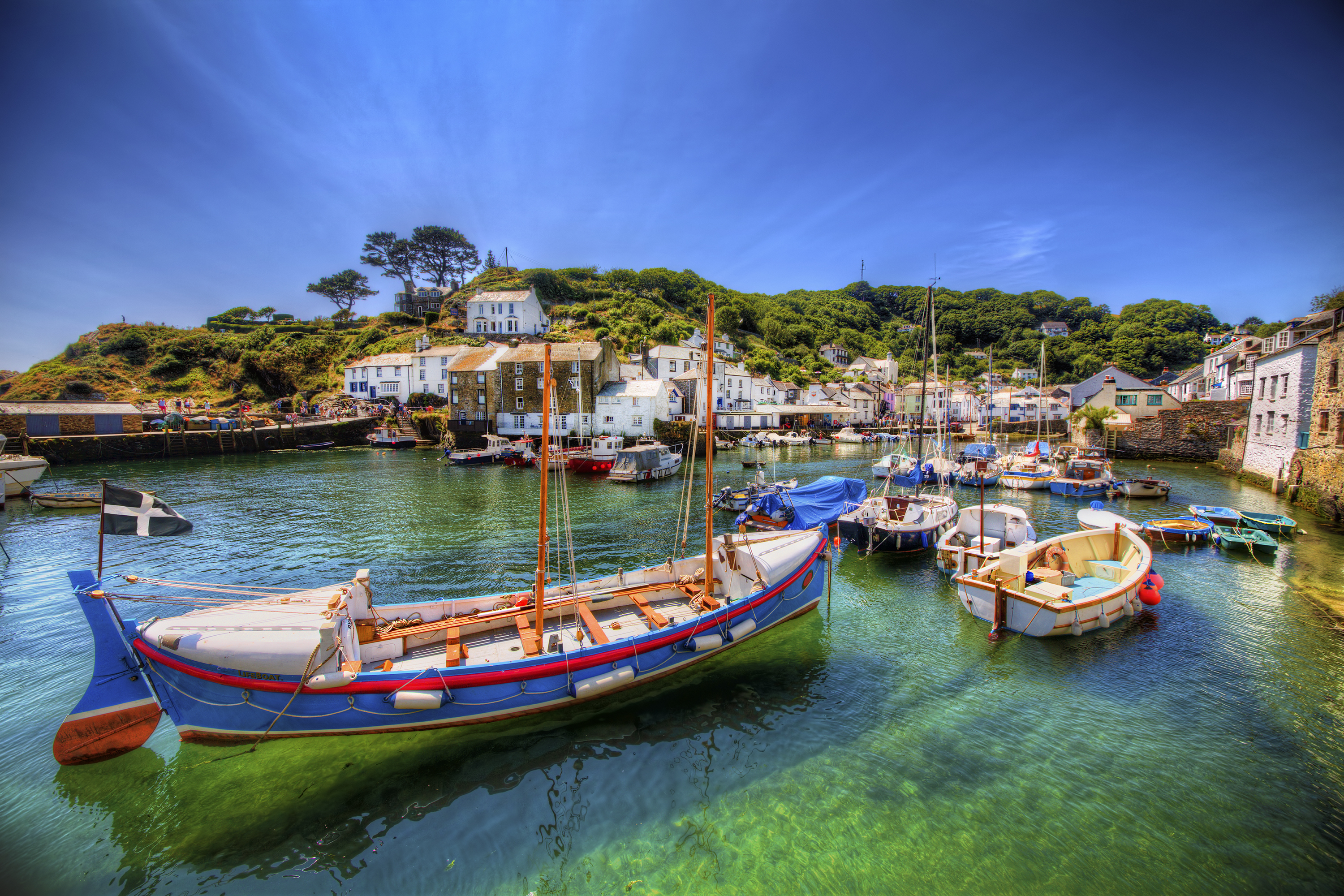 Stemningsfuld scene fra den pittoreske fiskerihavn i Polperro, en af Cornwalls mest fotogene kystbyer med farverige både og turkisblåt vand