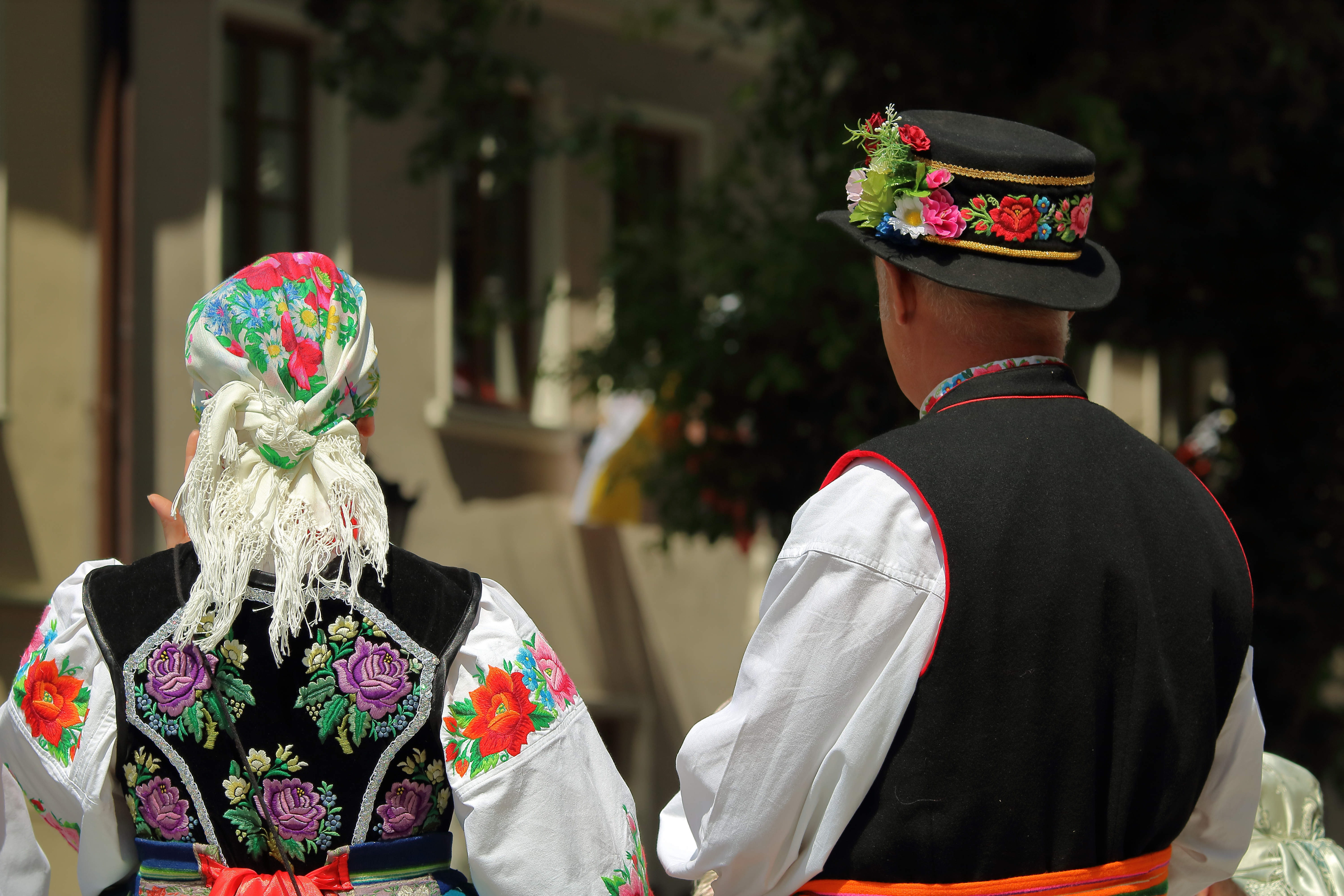 Traditionelle polske folkedragter med farverige broderede detaljer og blomsterhat