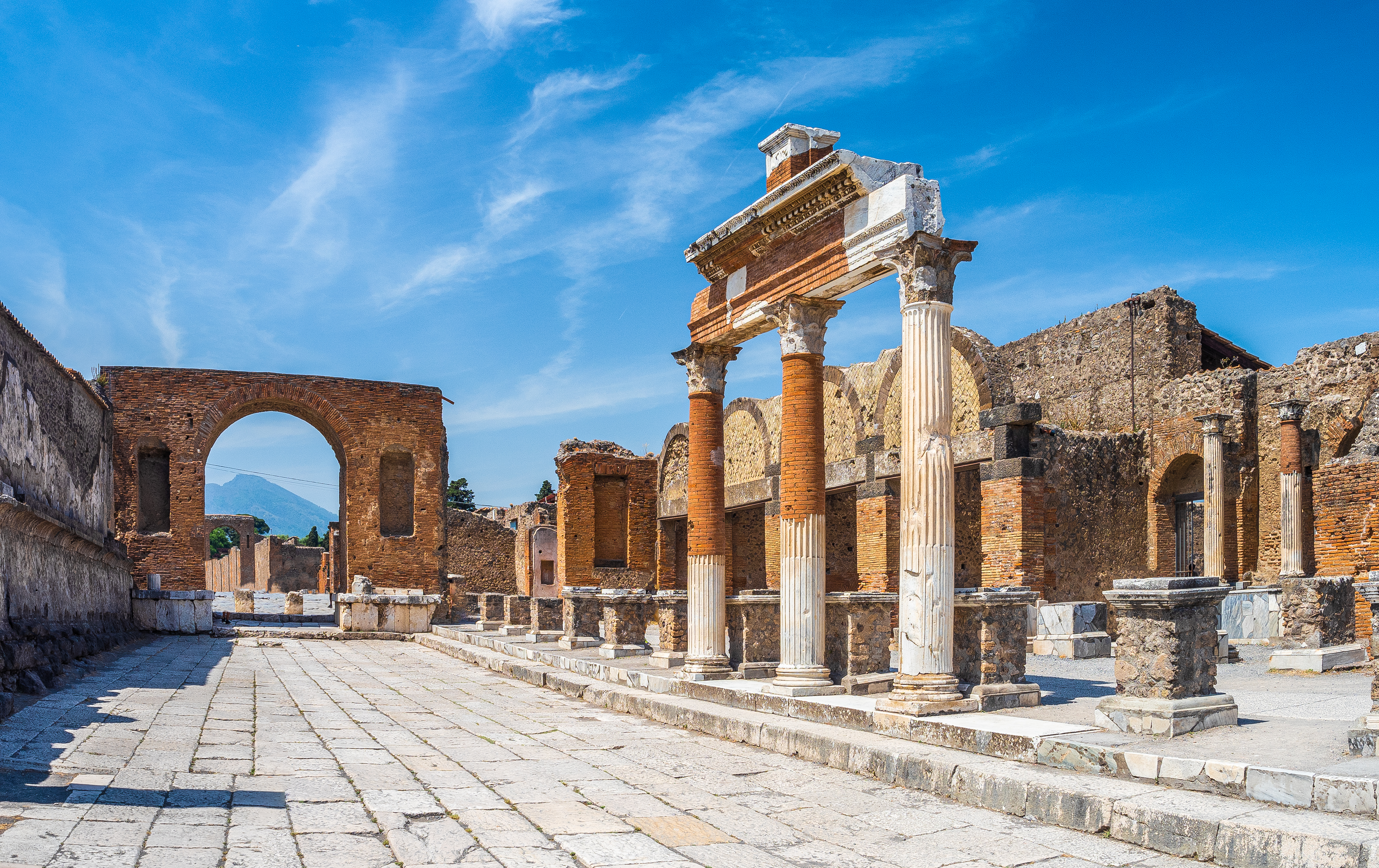 Pompejis velbevarede forum med antikke søjler og stenbro, vidnesbyrd om den romerske civilisation ved foden af Vesuv