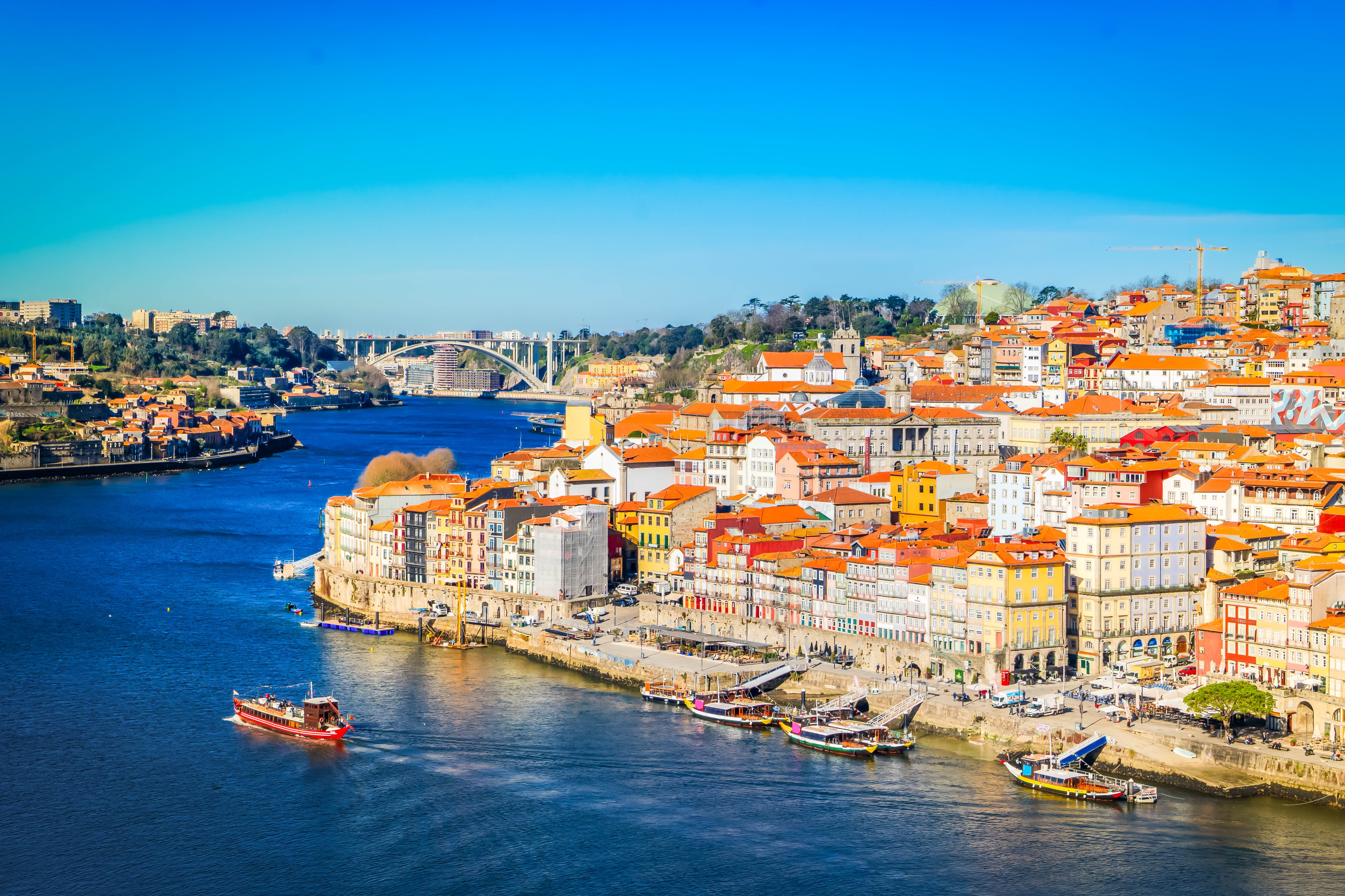 Panoramaudsigt over den historiske by Porto ved Douro-floden med farverige bygninger, traditionelle både og blå himmel