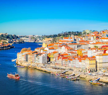 Panoramaudsigt over den historiske by Porto ved Douro-floden med farverige bygninger, traditionelle både og blå himmel