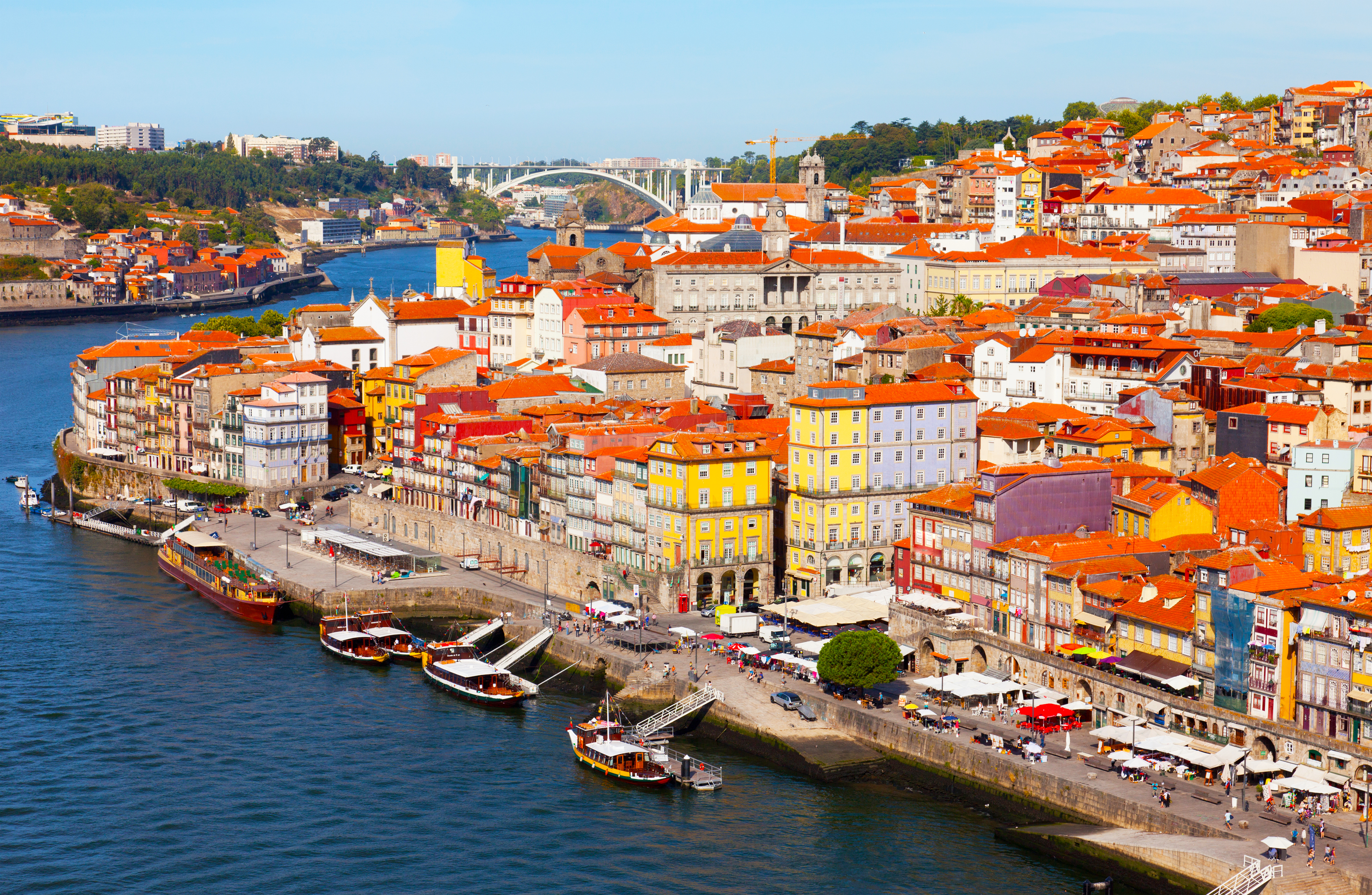 Malerisk panoramaudsigt over Portos historiske bymidte med karakteristiske bygninger og rødlige tage ved Douro-floden i morgenlyset