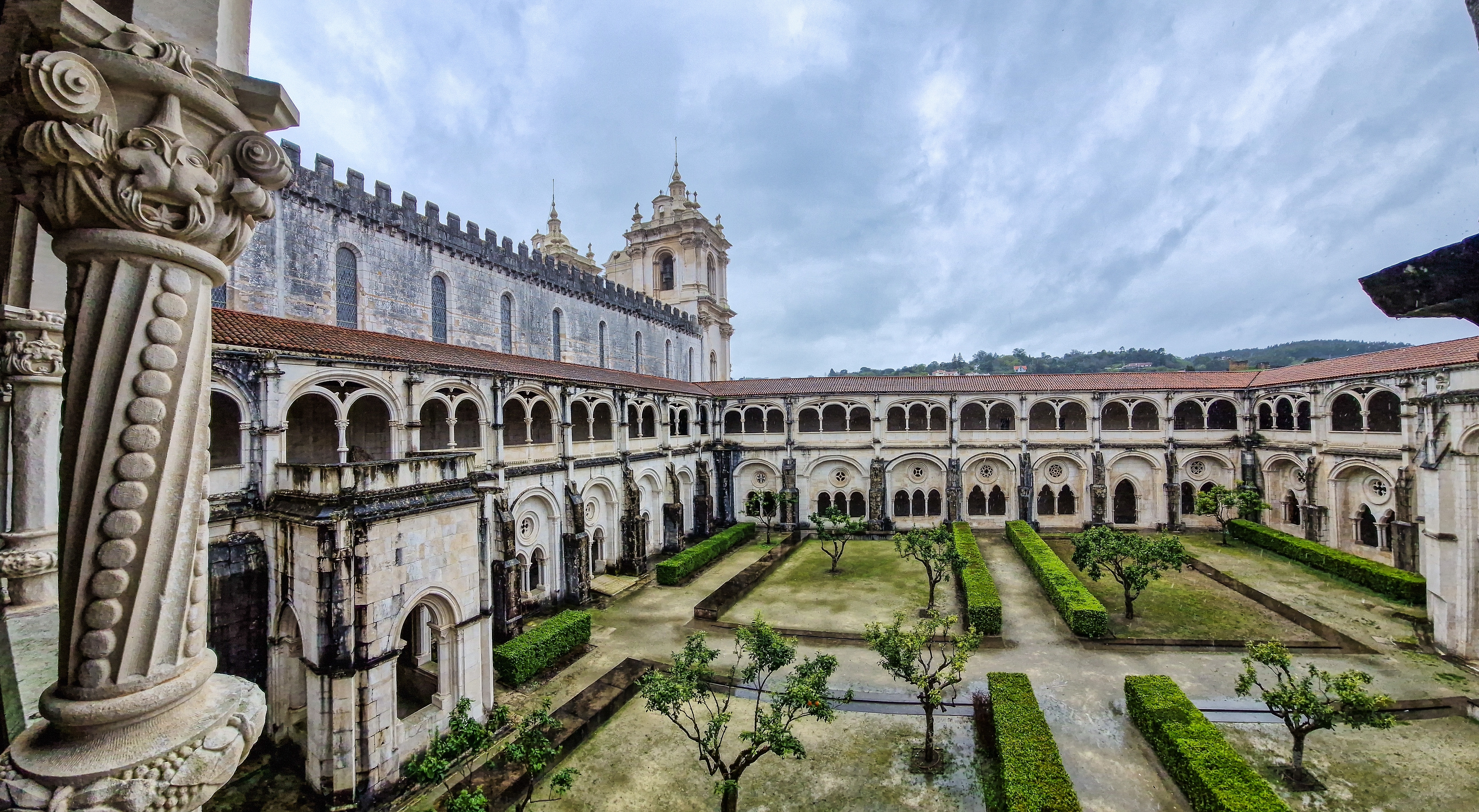 Imponerende gotisk kloistergård i det historiske Alcobaça Kloster i Portugal med smukke stensøjler og velplejet klosterhave