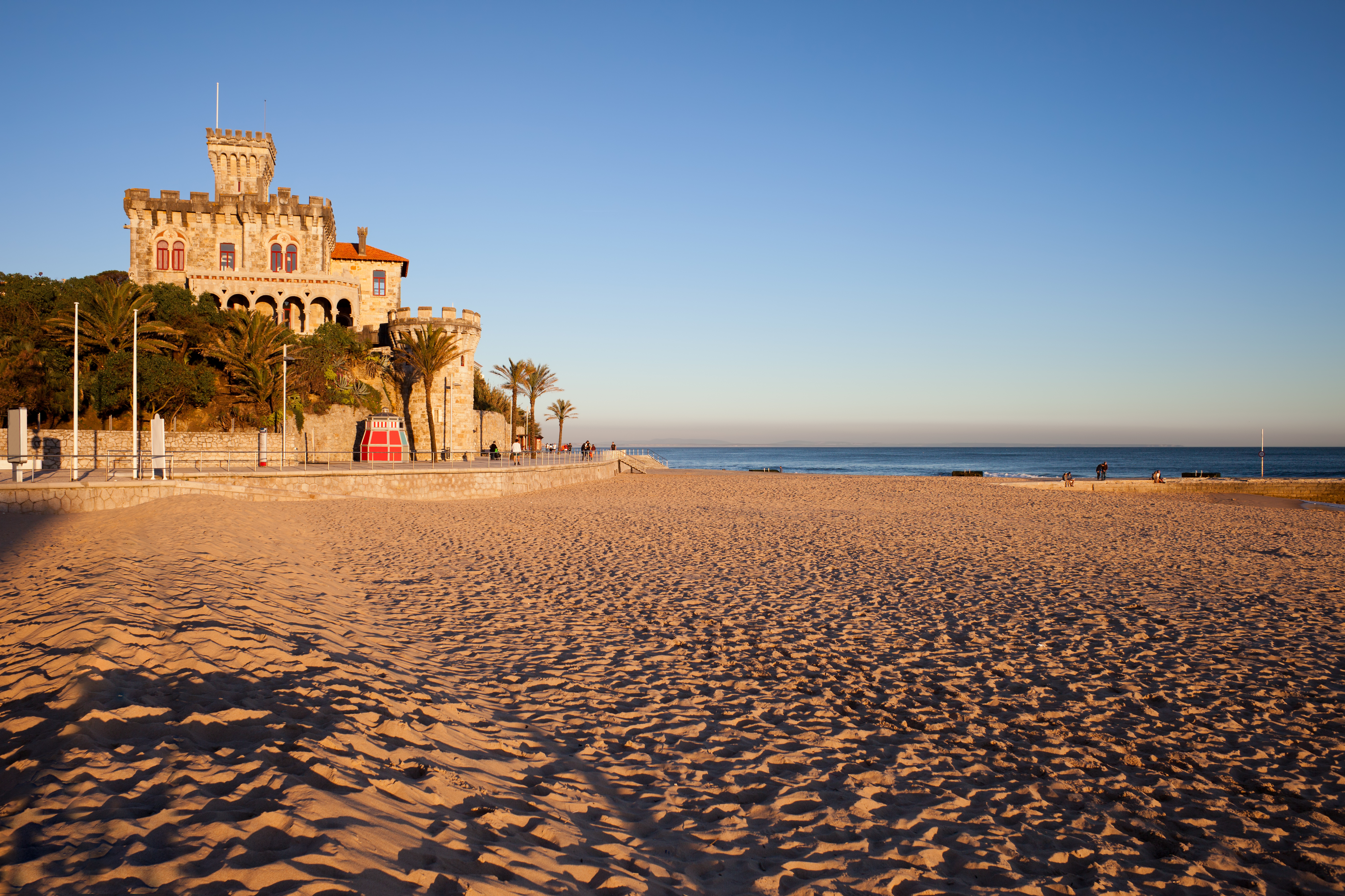 Rolig sandstrand ved Estoril i Portugal med historisk slot og palmer ved den portugisiske Atlanterhavskyst