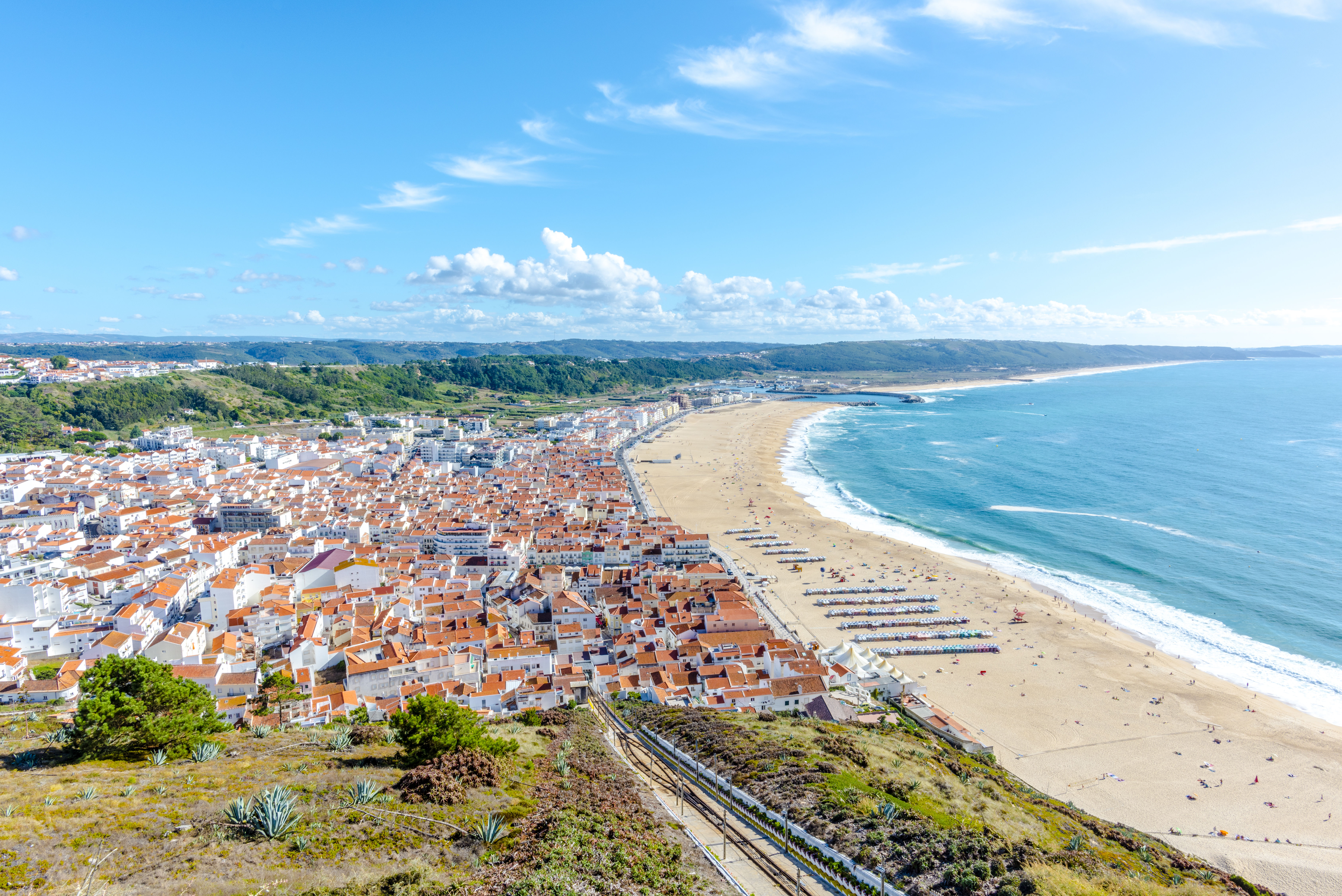 Luftbillede af Nazare strand i Portugal med traditionelle huse og smuk kystlinje