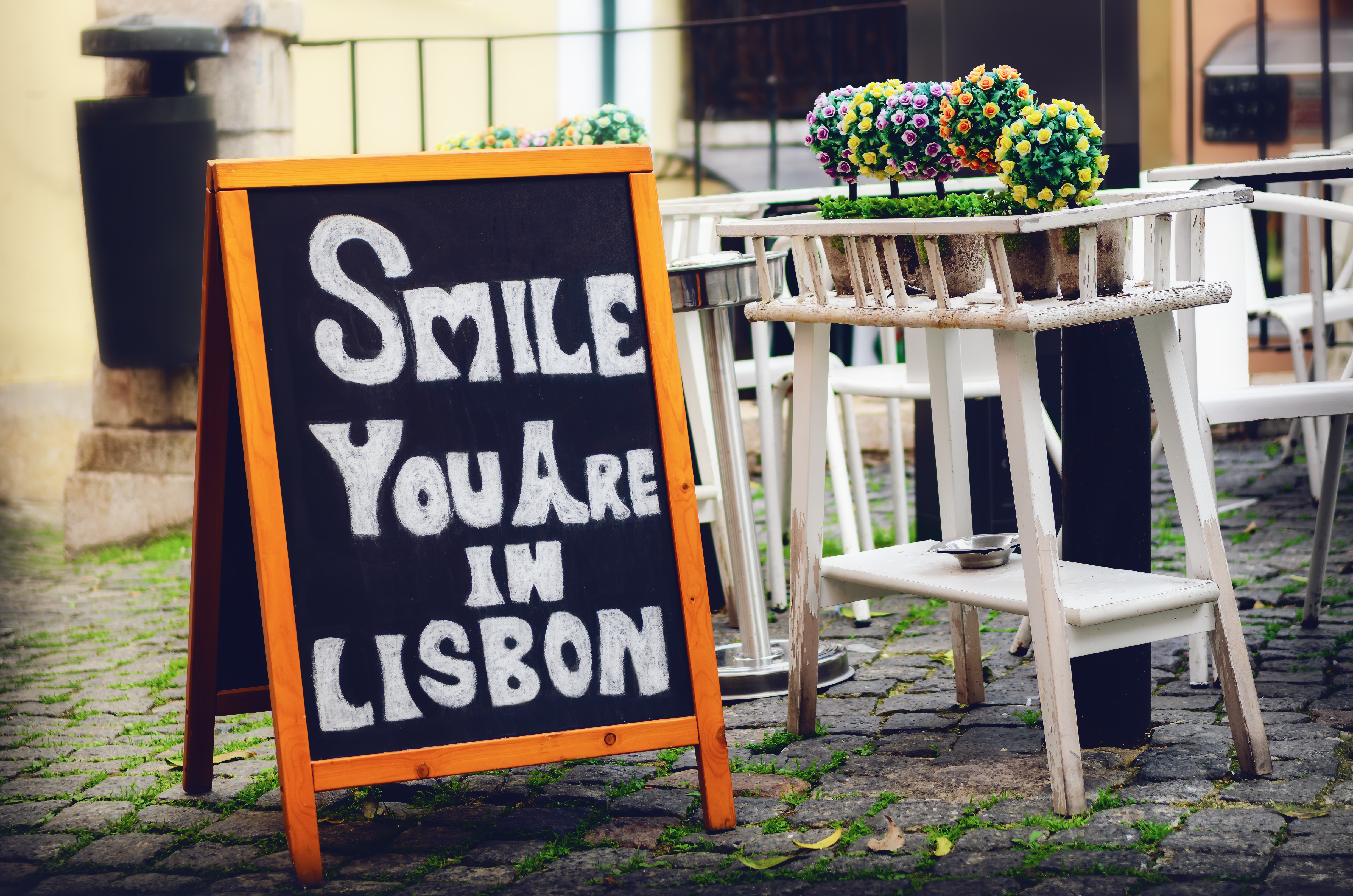 Sort tavle med den glade besked "Smile you are in Lisbon" i det maleriske Alfama-kvarter, Lissabons historiske hjerte med fado-musik og traditionsrige restauranter