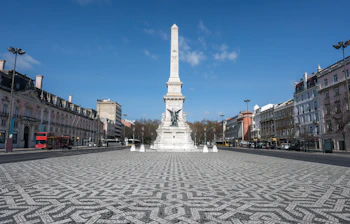 Den historiske Praça dos Restauradores i Lissabon med det smukke hvide monument og den karakteristiske portugisiske brosten-mosaik på pladsen