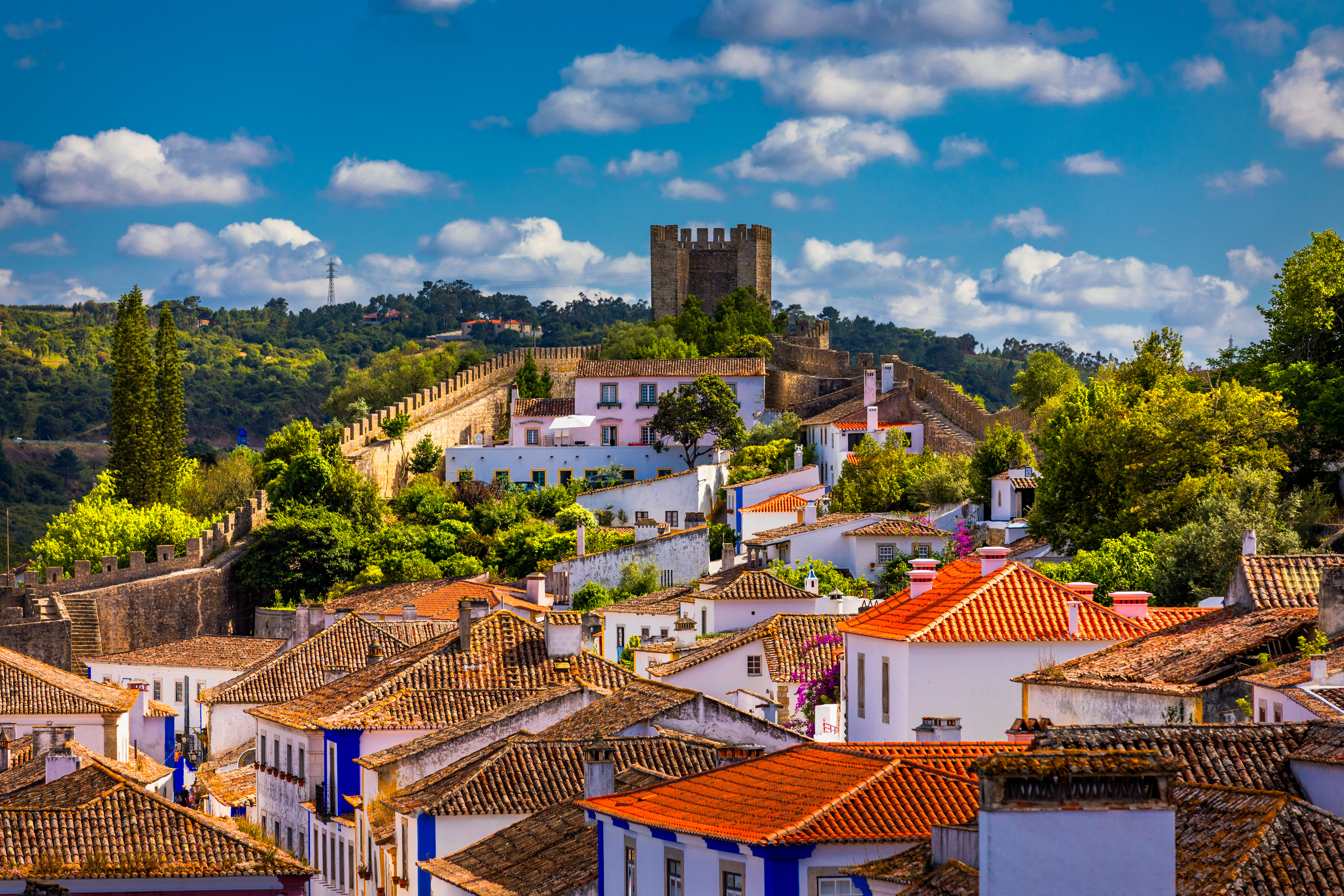 Det smukke taglandskab i den historiske fæstningsby Óbidos i Portugal med dens karakteristiske arkitektur, hvide facader og røde teglsten - en kulturperle på vores rundrejse
