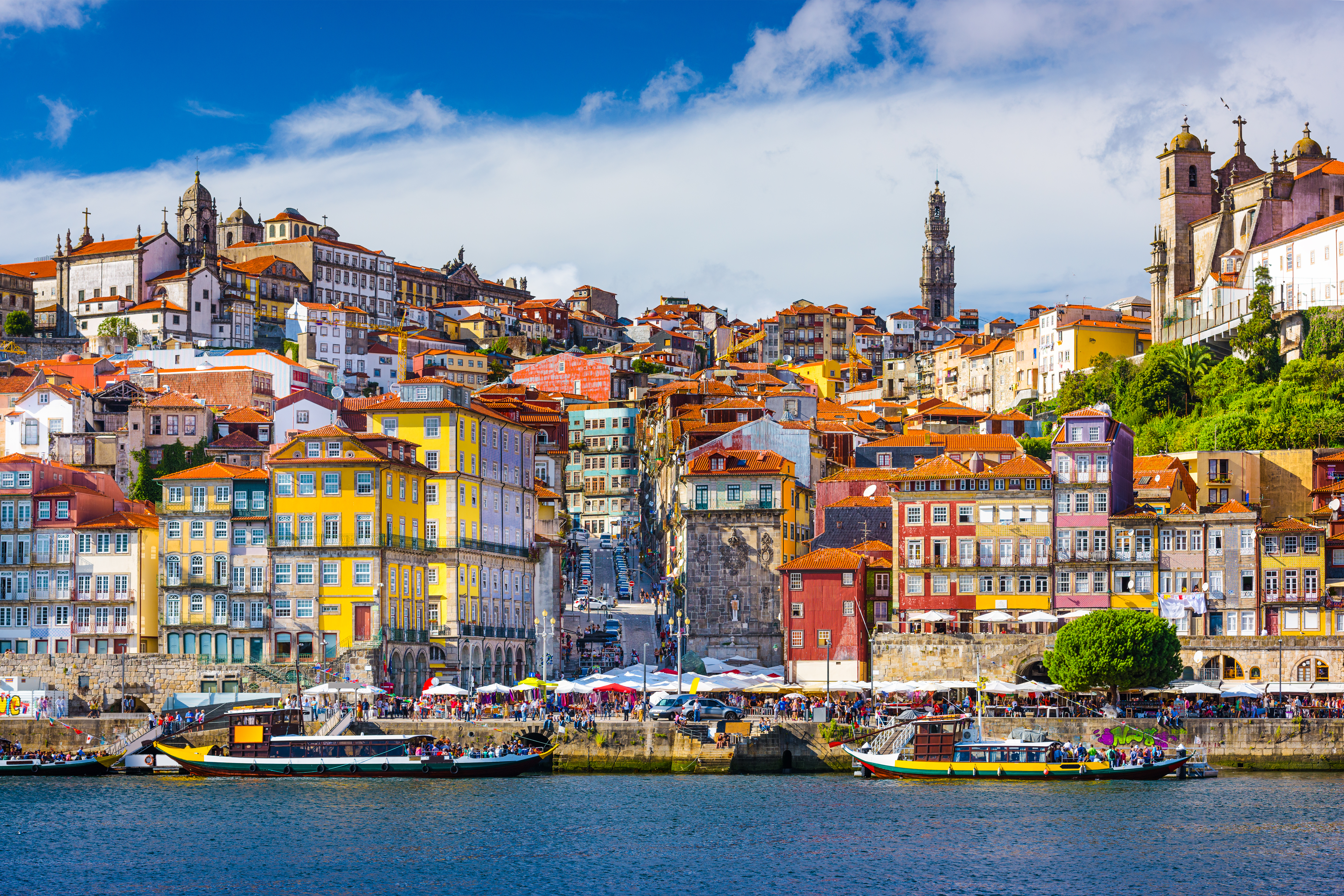 Smukke farverige huse ved Douro-flodens bred i Porto med både og blå himmel