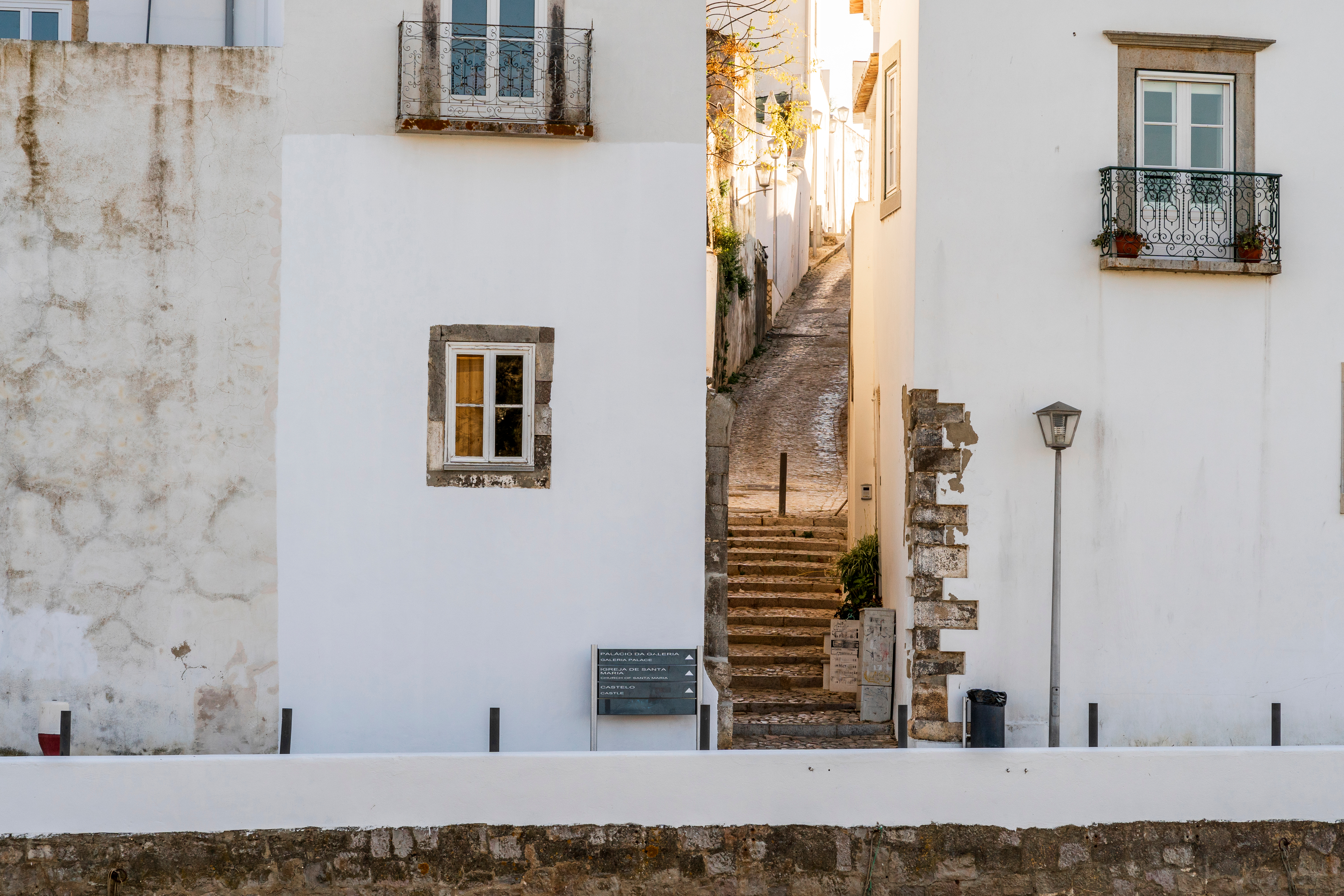Klassisk portugisisk byarkitektur med hvide facader og jernbalkoner i Tavira