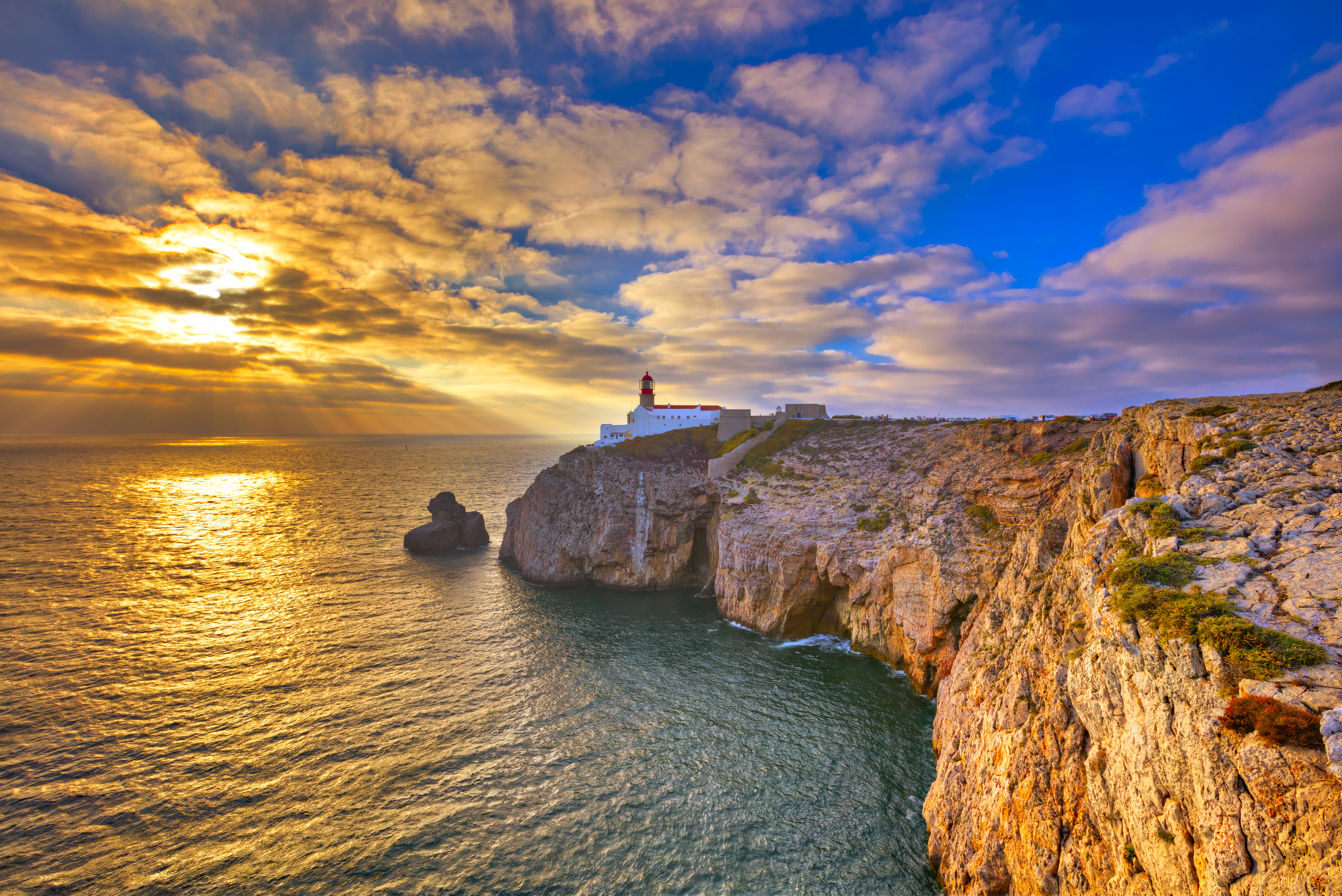 Fyrtårn på Portugals vestkyst med gylden solnedgang over Atlanterhavet