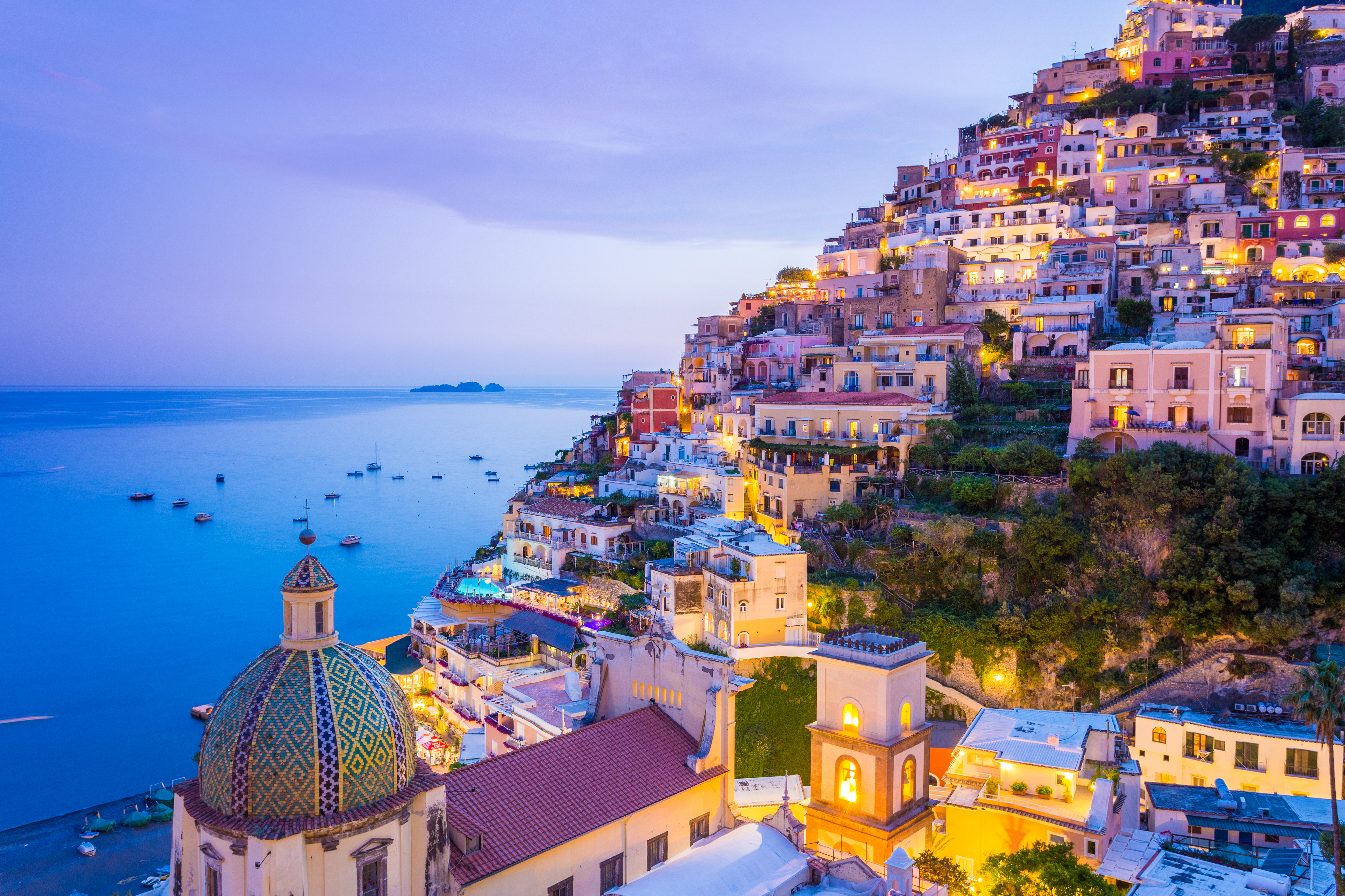 Panoramaudsigt over Positano på Amalfikysten med solnedgang og farverige bygninger
