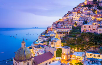 Panoramaudsigt over Positano på Amalfikysten med solnedgang og farverige bygninger