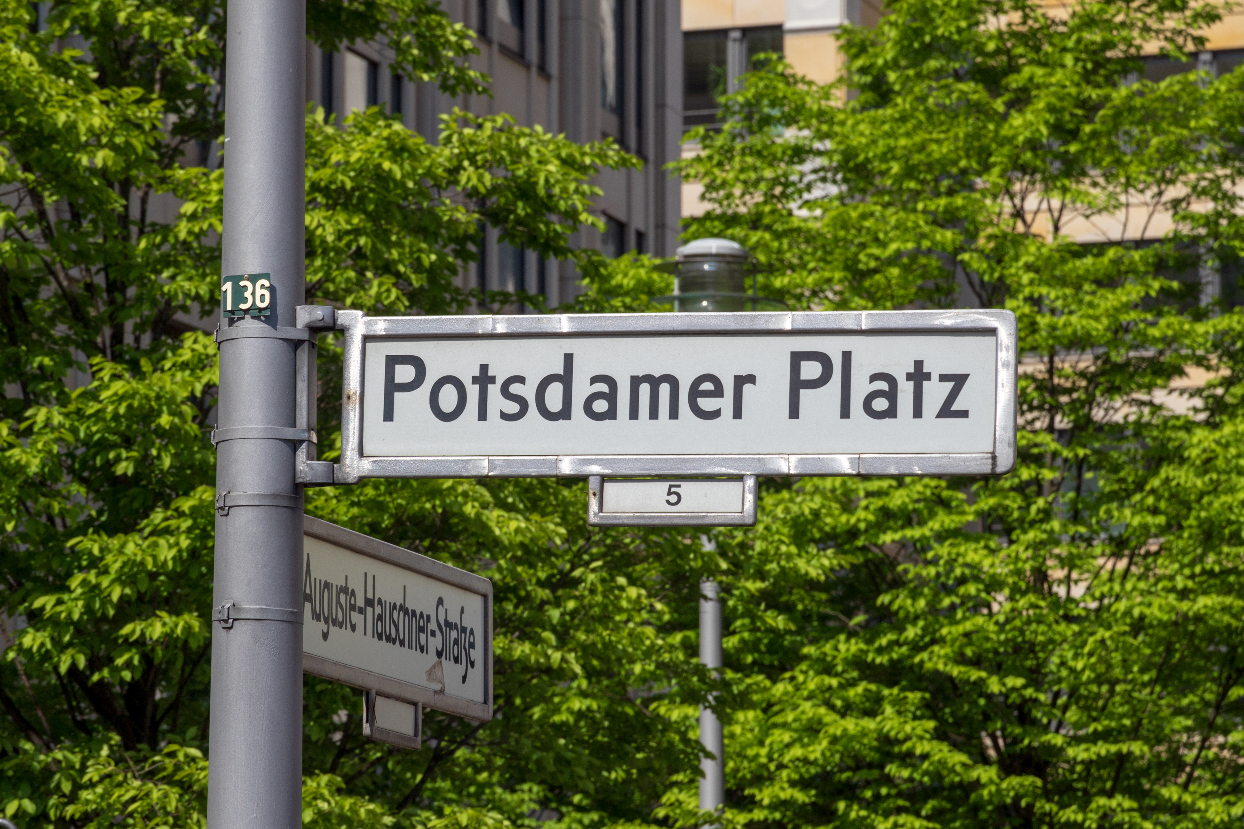 Hvide byskilte ved Potsdamer Platz i Berlin centrum med grønne træer omkring