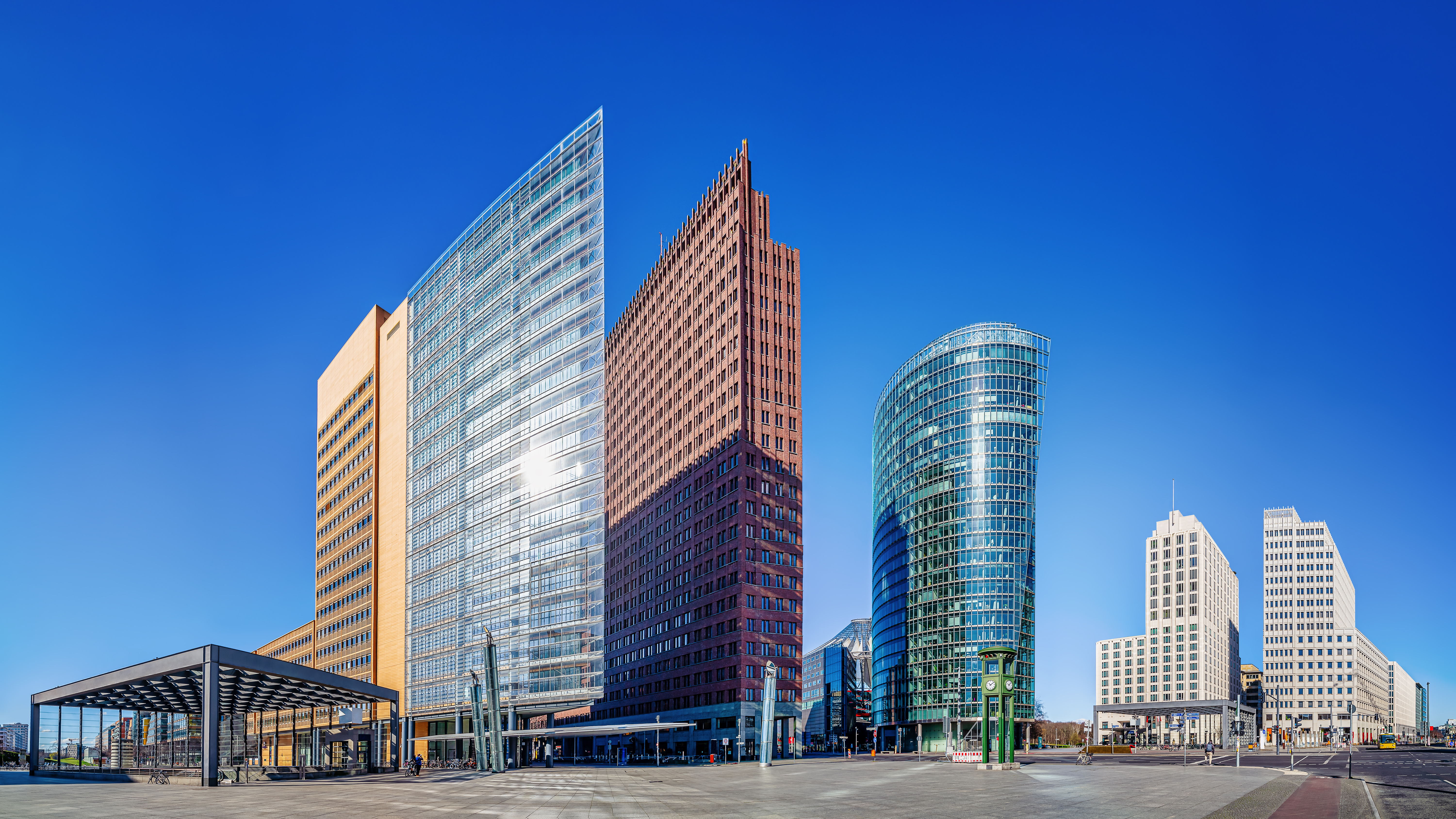 Berlins ikoniske Potsdamer Platz med moderne skyskrabere og spejlende glasfacader under blå himmel