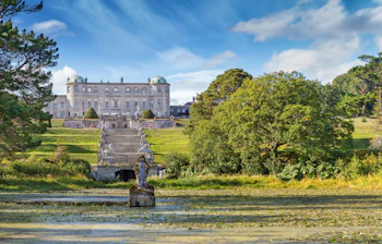 Magisk udsigt over Powerscourt Estate i Enniskerry, Irland, med det historiske herresæde, skulpturprydede havestier og en rolig sø dækket af åkander
