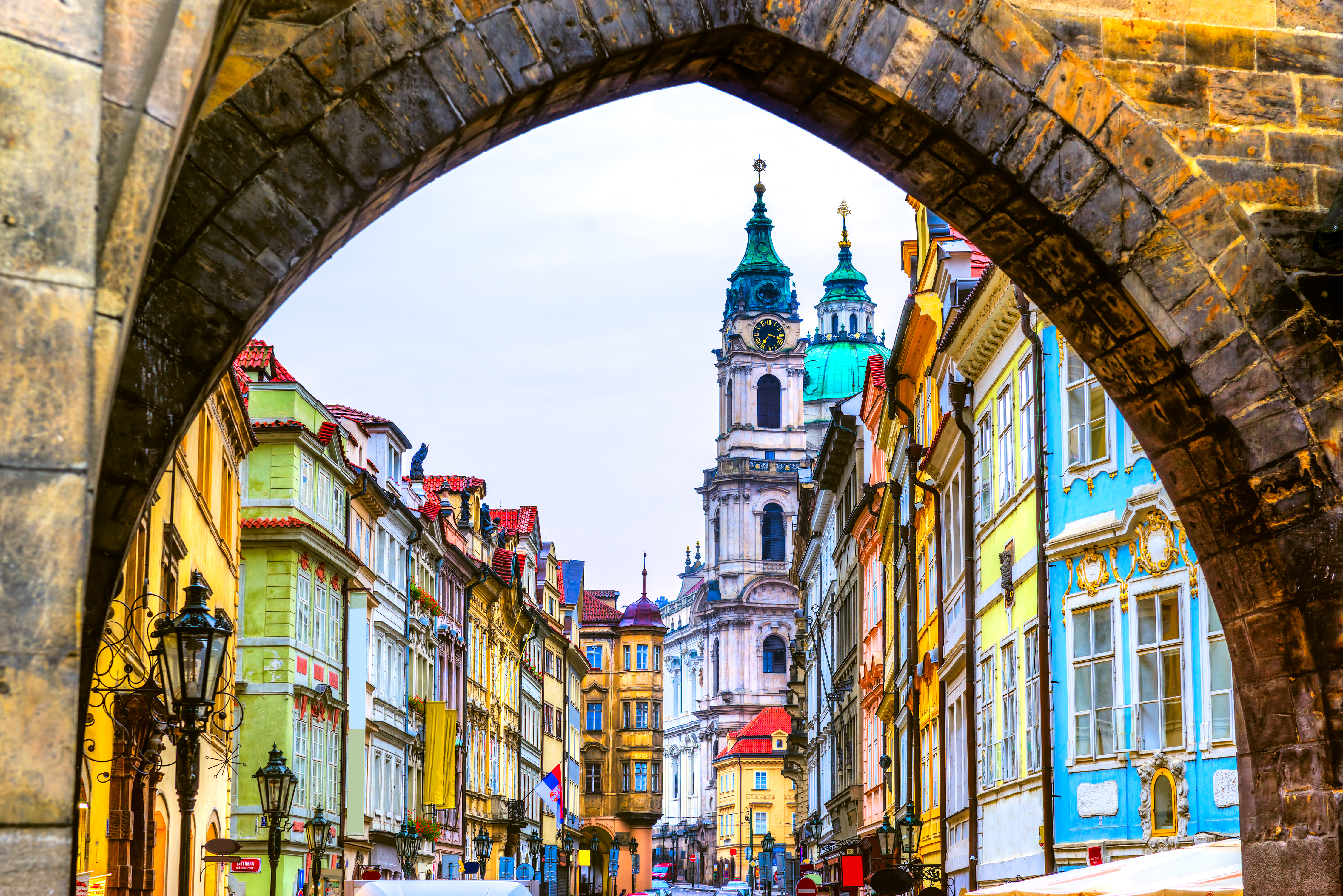 Farverige bygninger i Mala Strana set gennem stenbuet portal på Karlsbroen med Sankt Nikolaj Kirken i Prag, Tjekkiet