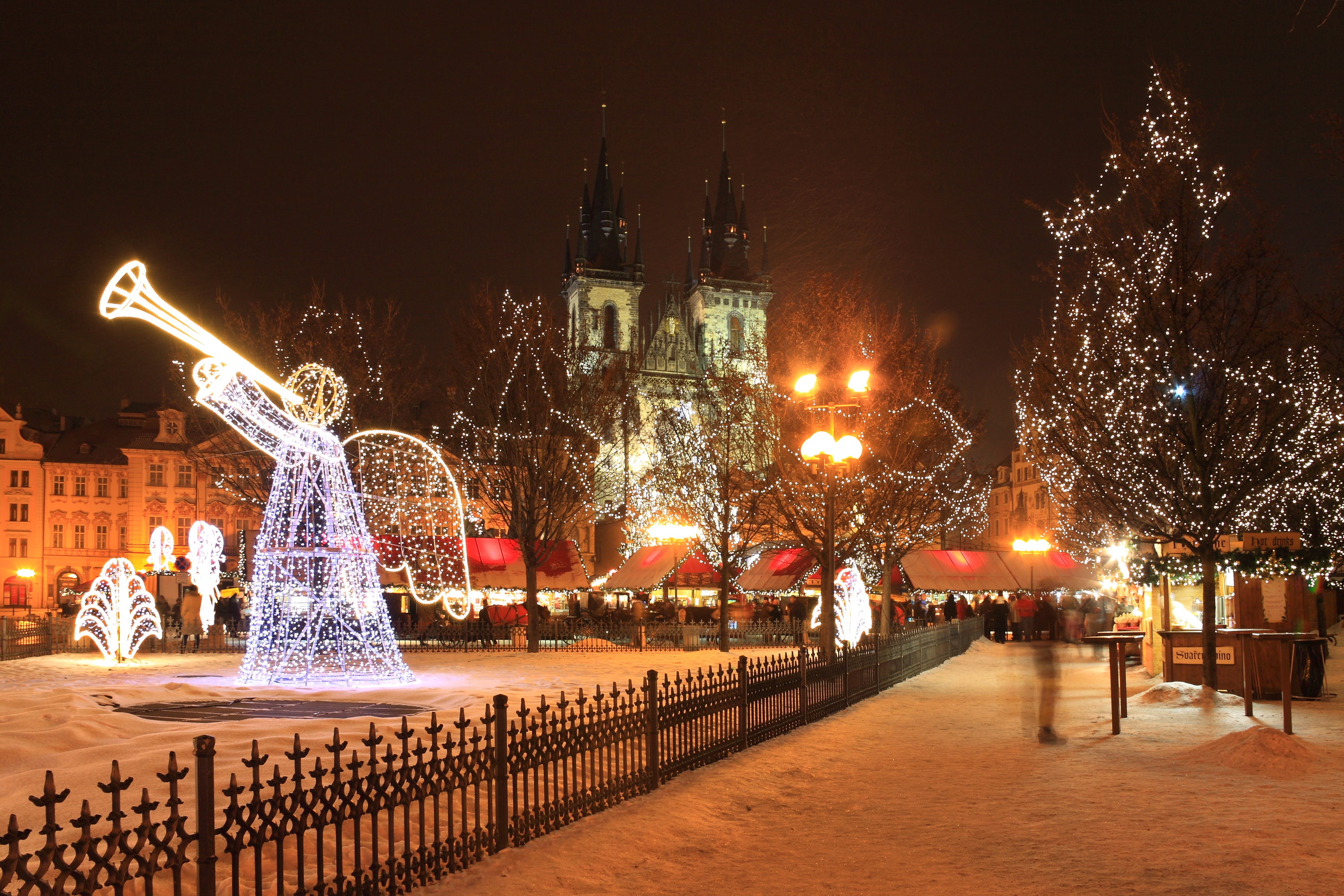 Vinterjulemarked på Gamle Torv i Prag med smuk lysengel og Tyn-katedralen i baggrunden under snefald