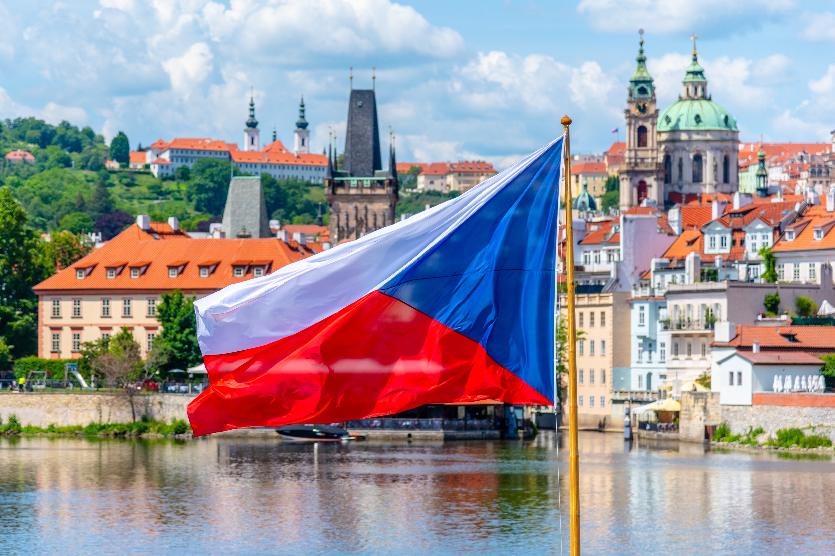 Praha byudsigt med vajende tjekkisk flag og historiske tårne
