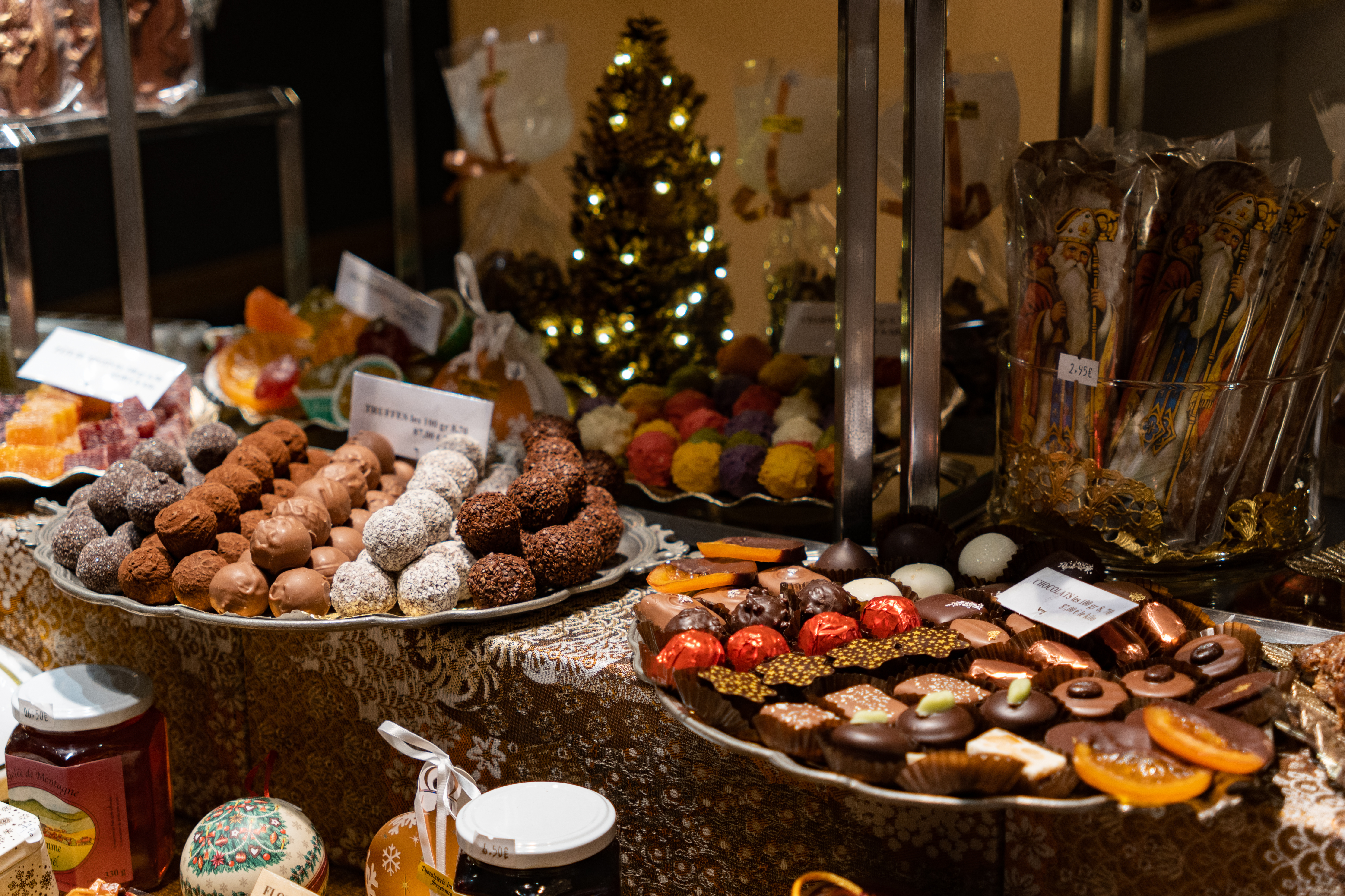 Farverige chokoladepralines og trøfler på sølvfade i en julepyntet chokoladebutik i Alsace