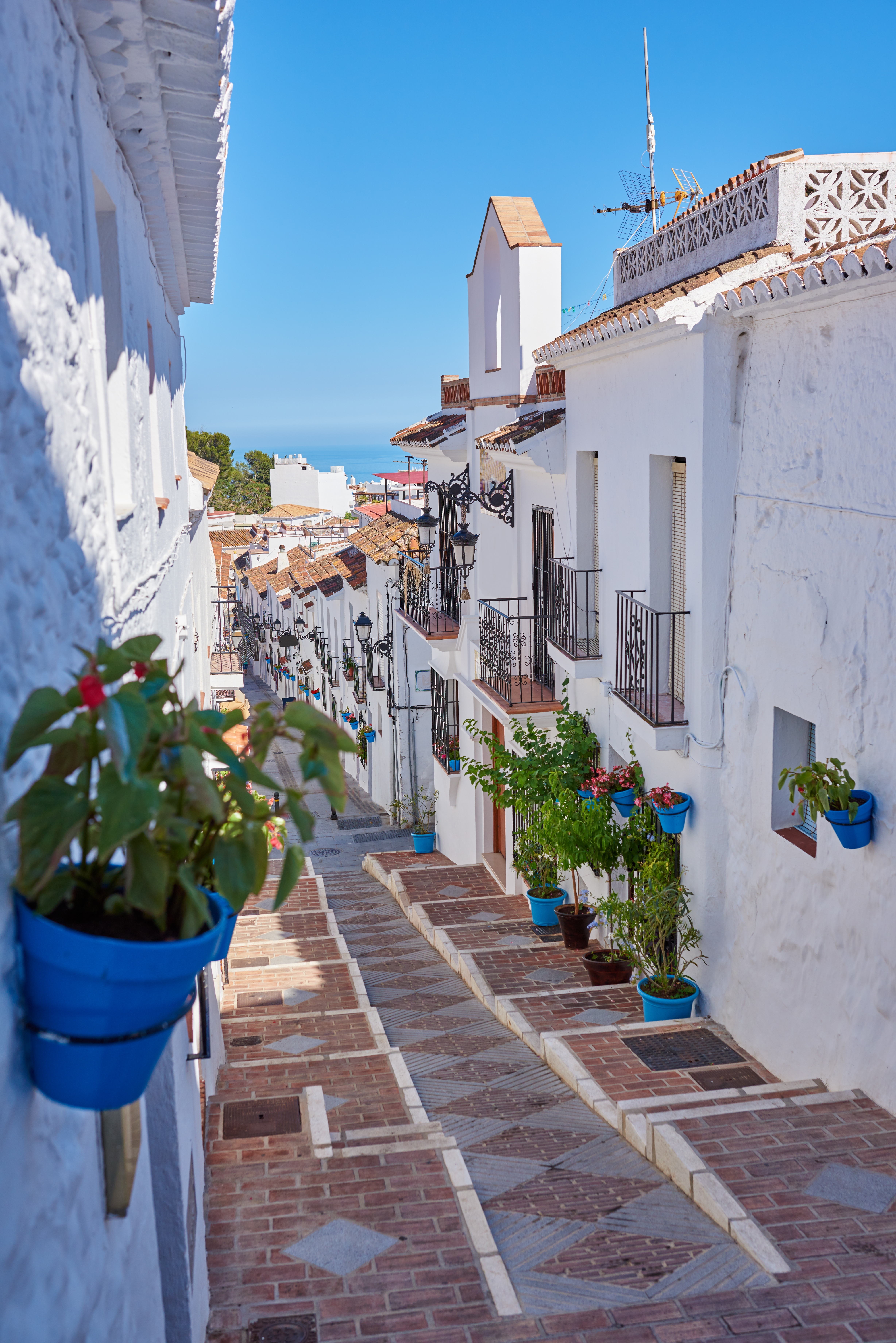 Charmerende hvide andalusiske landsby med blå blomsterkrukker og traditionel arkitektur