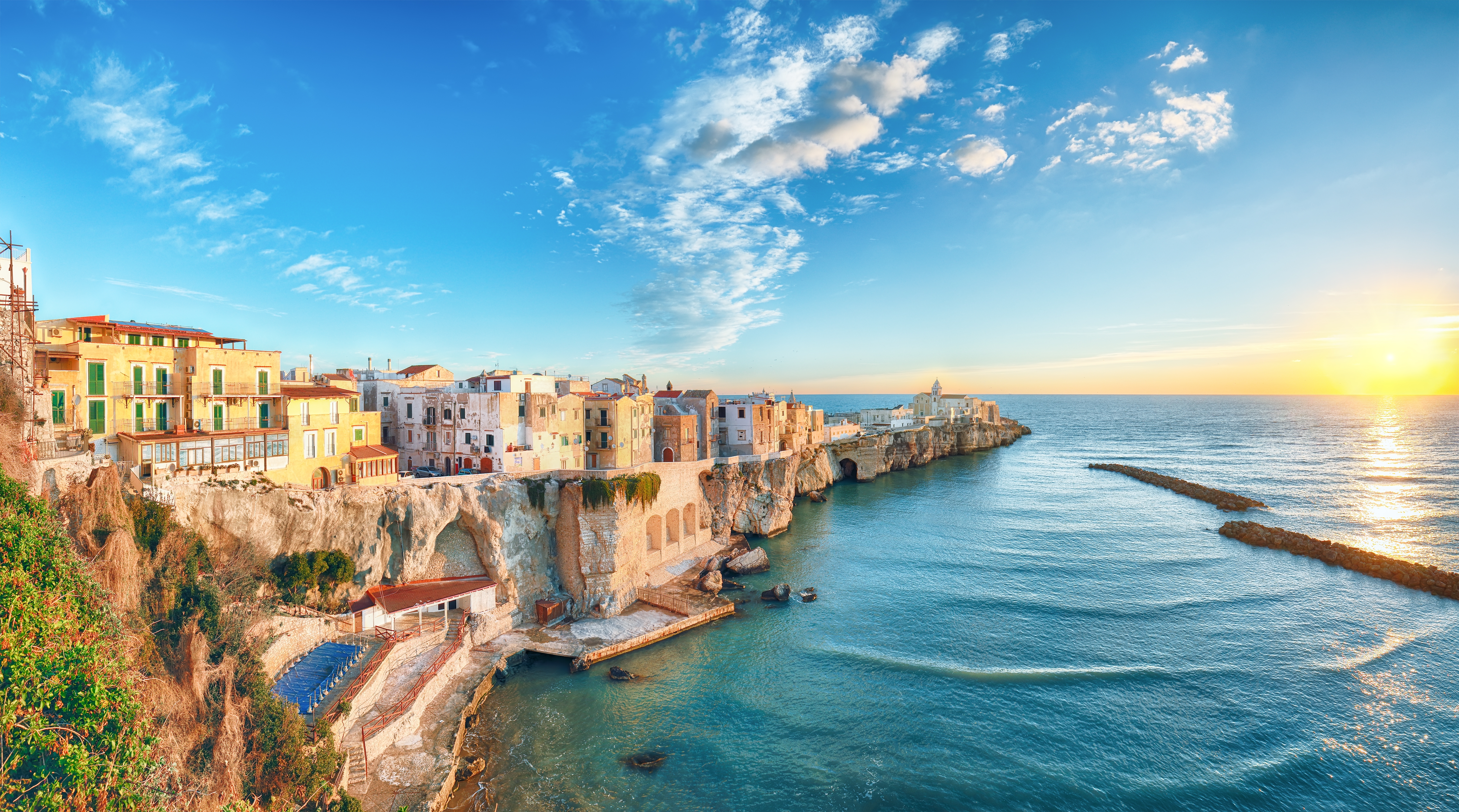 Betagende udsigt over den idylliske kystby Vieste med San Francesco kirken og de hvide huse, der klamrer sig til klipperne over det azurblå Adriaterhav i Puglia