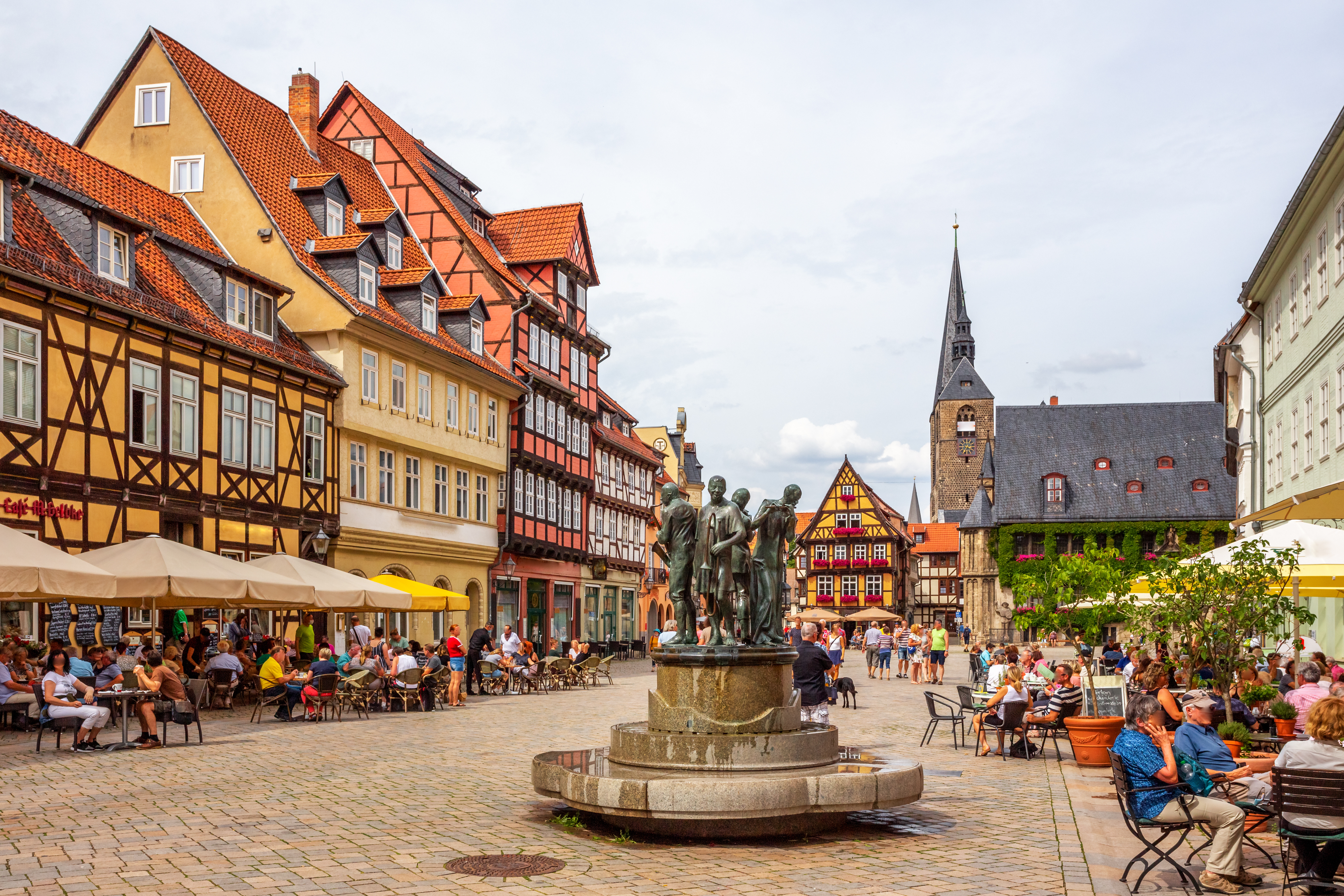 Stemningsfuldt torv i Quedlinburg omgivet af farverige bindingsværkshuse og travle caféer med turister nyder sommervejret i Sachsen-Anhalt