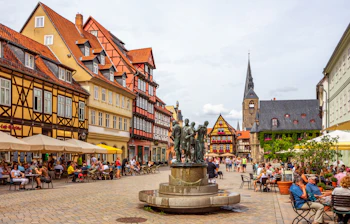 Stemningsfuldt torv i Quedlinburg omgivet af farverige bindingsværkshuse og travle caféer med turister nyder sommervejret i Sachsen-Anhalt