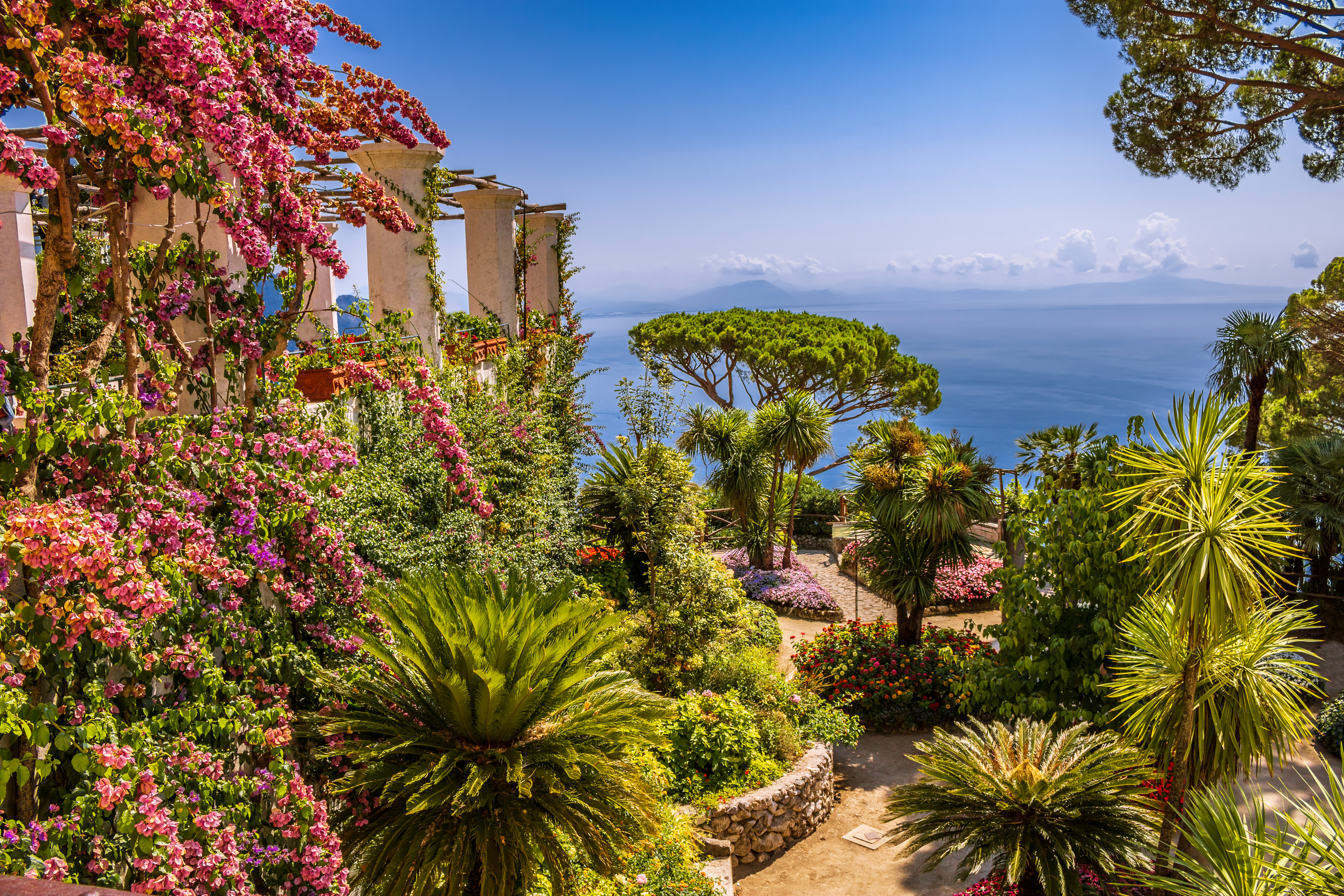 Smuk og farverig blomsterhave ved Villa Rufolo i Ravello på Amalfkysten i Italien med palmer og udsigt over Middelhavet