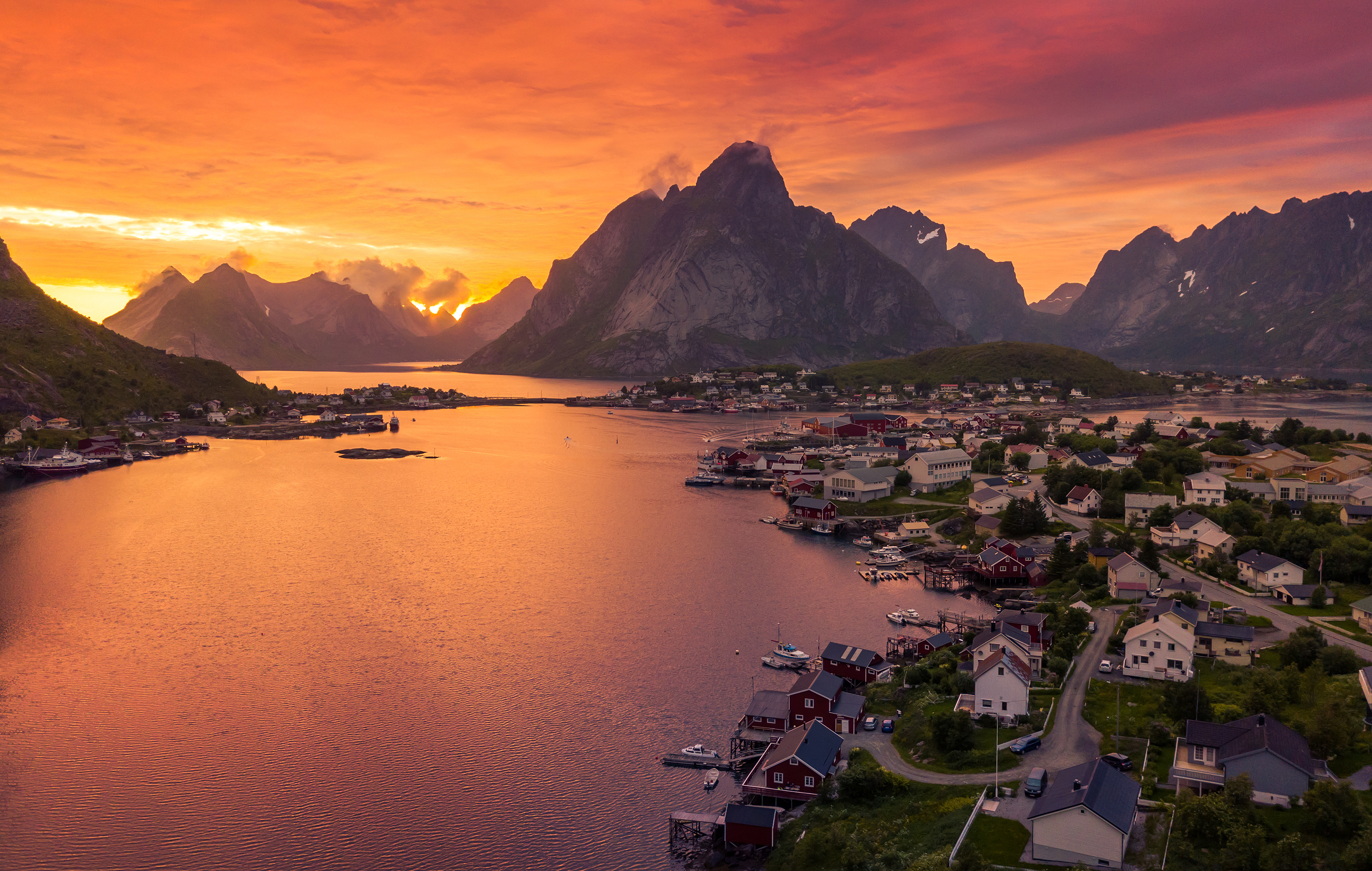 Reine fiskerlandsby på Moskenesøya i Lofoten under en spektakulær solnedgang med orange himmel