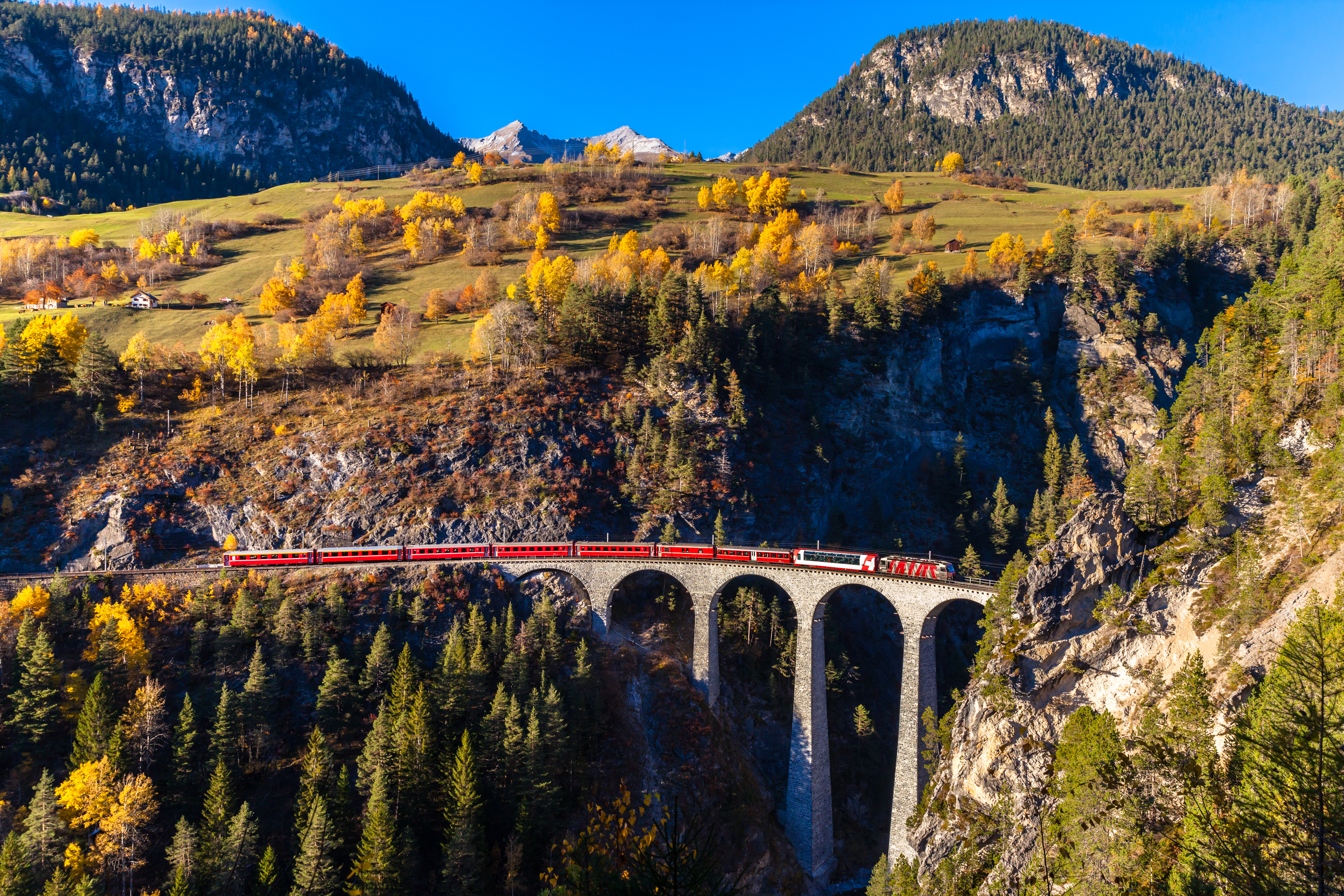 UNESCO-fredet Landwasser Viadukt med det røde Glacier Express tog gennem efterårets farvepragt i Graubünden, Schweiz