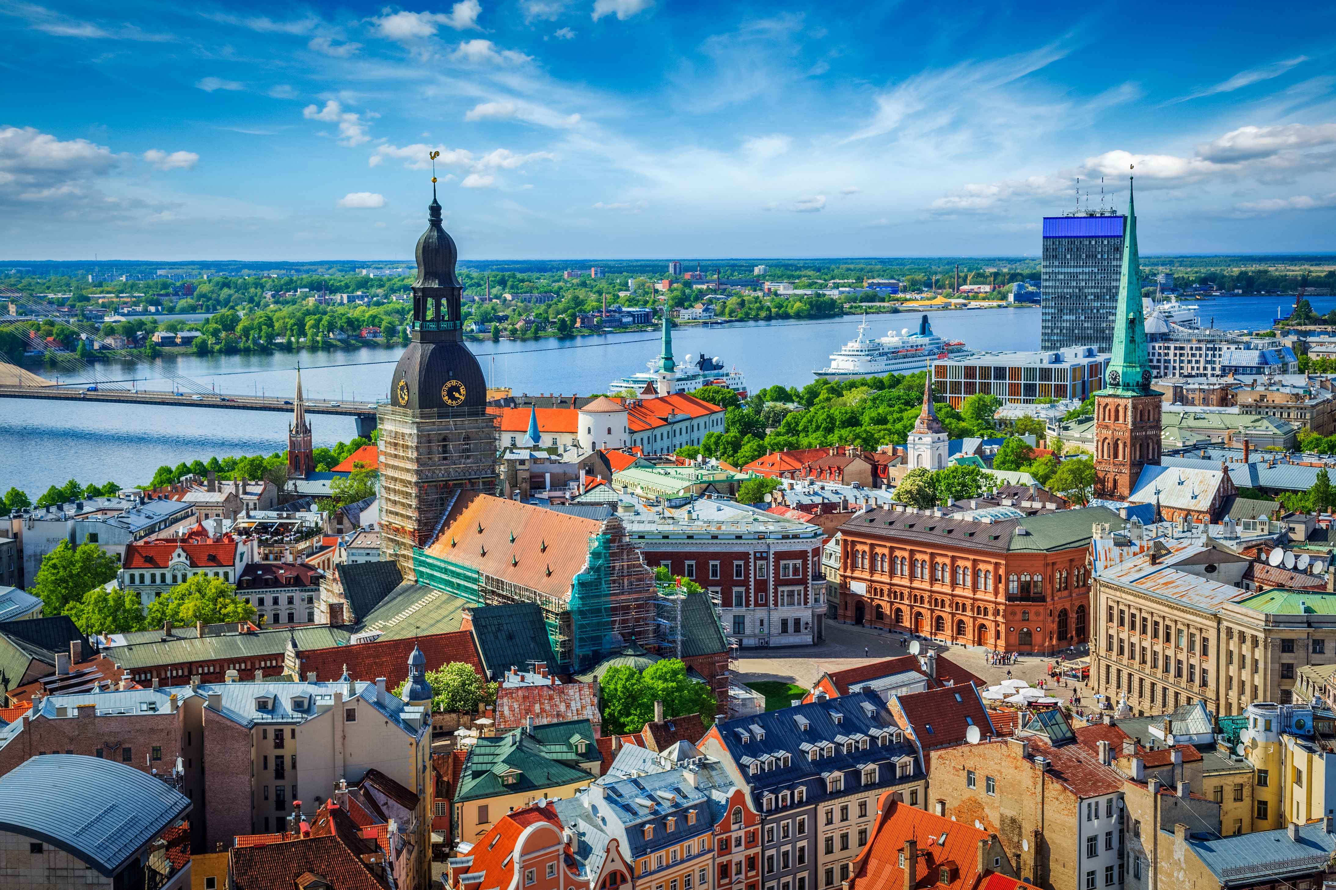 Imponerende panoramaudsigt over Rigas historiske bymidte med gamle bygninger, kirketårne og Daugava-floden under blå himmel