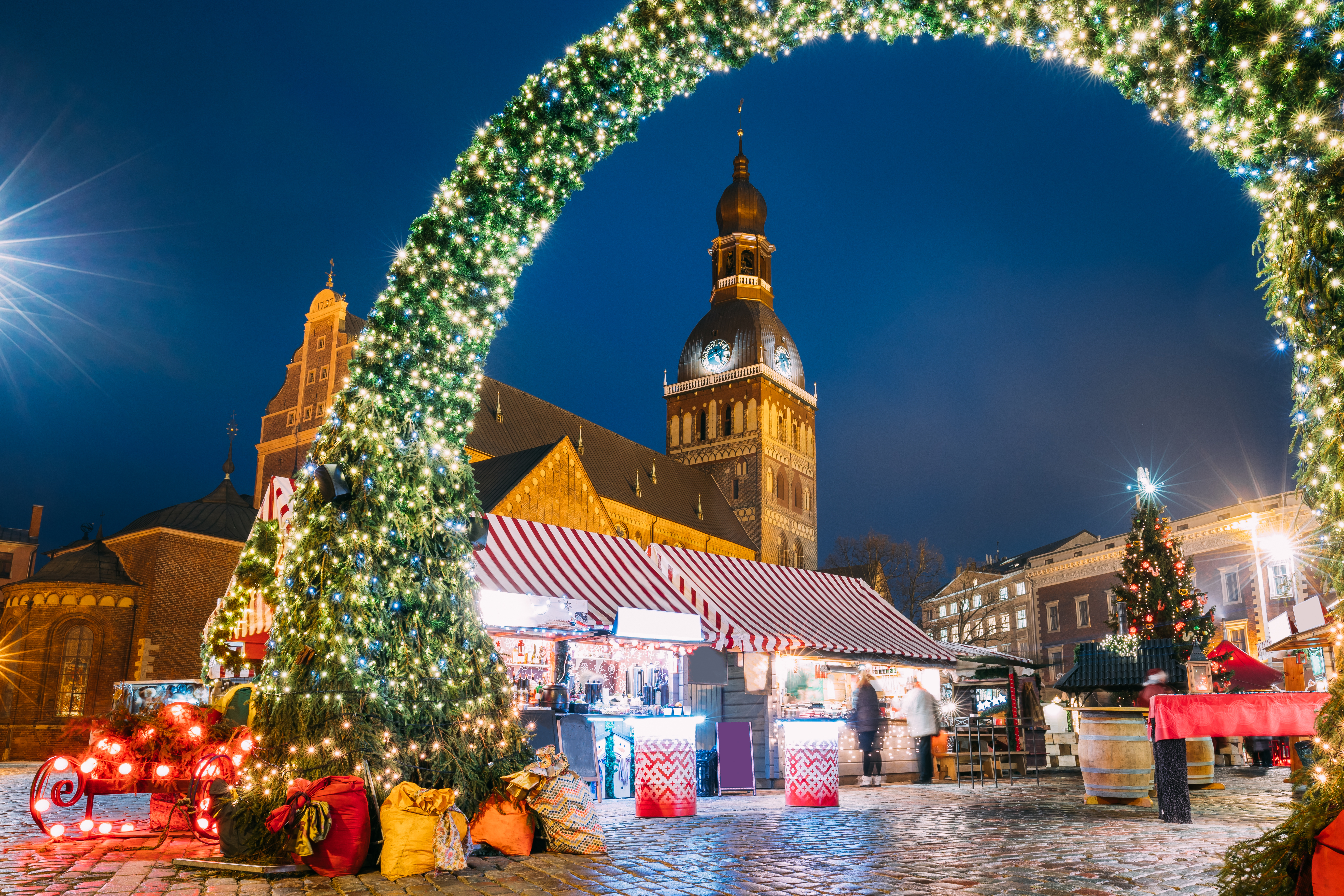 Magisk vinteraften på julemarkedet ved Domkirkepladsen i Riga med den historiske domkirke og festlige markedsboder
