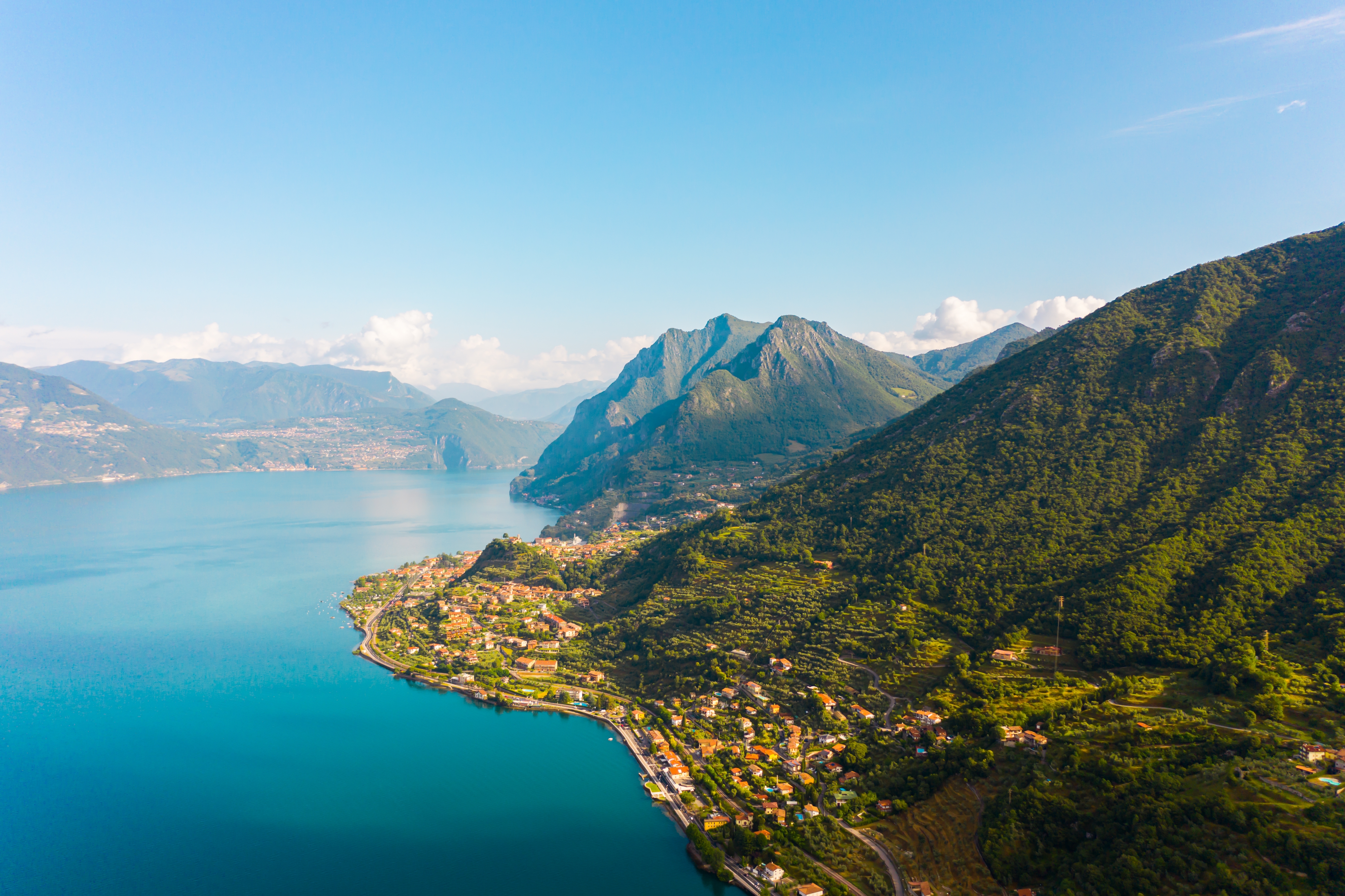 Storslået luftfoto af Gardasøen med den historiske by Riva del Garda omgivet af imponerende bjerge og krystalklart vand
