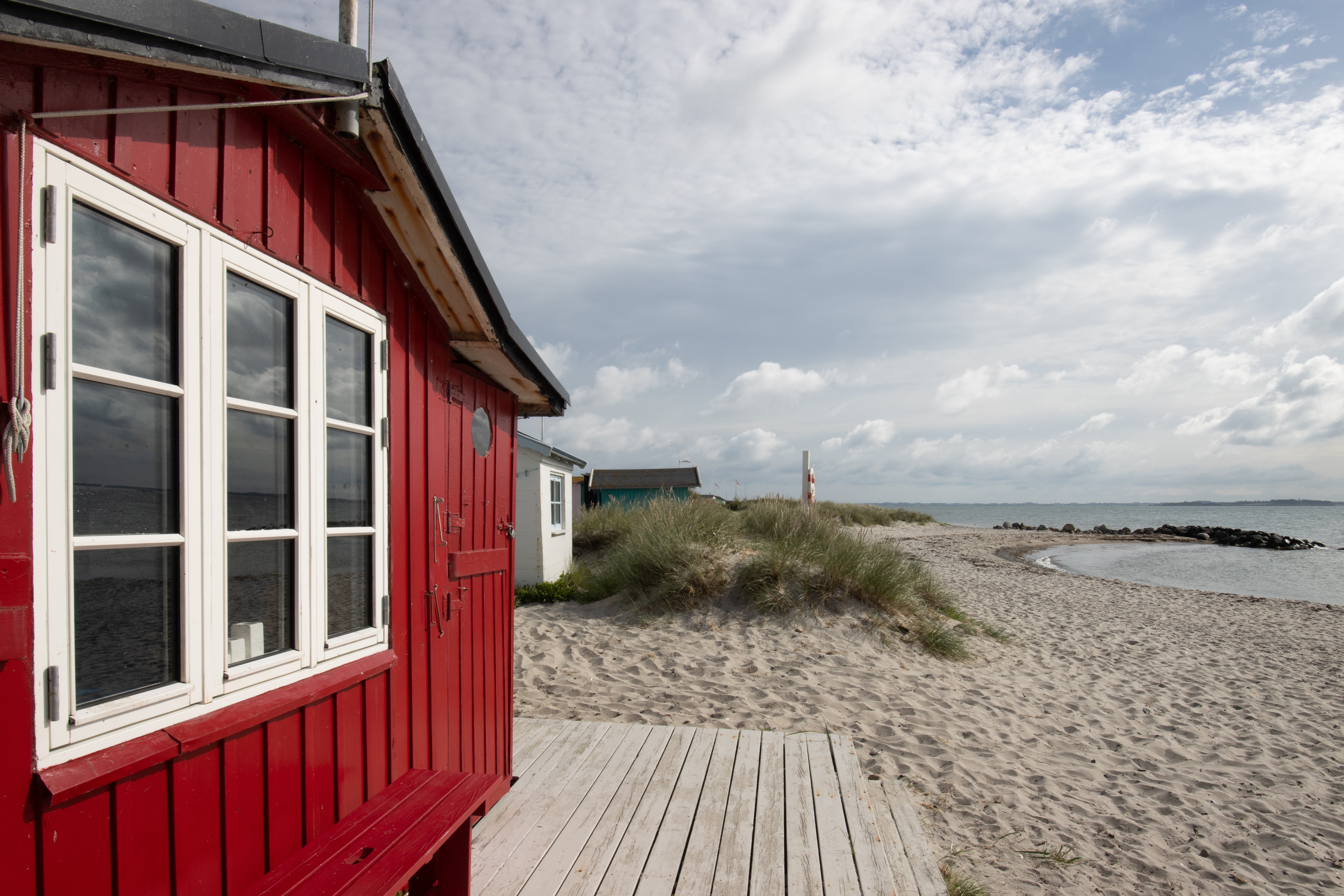 Smuk rød træhytte på sandstranden ved Eriks Hale, Marstal, Ærø i Danmark