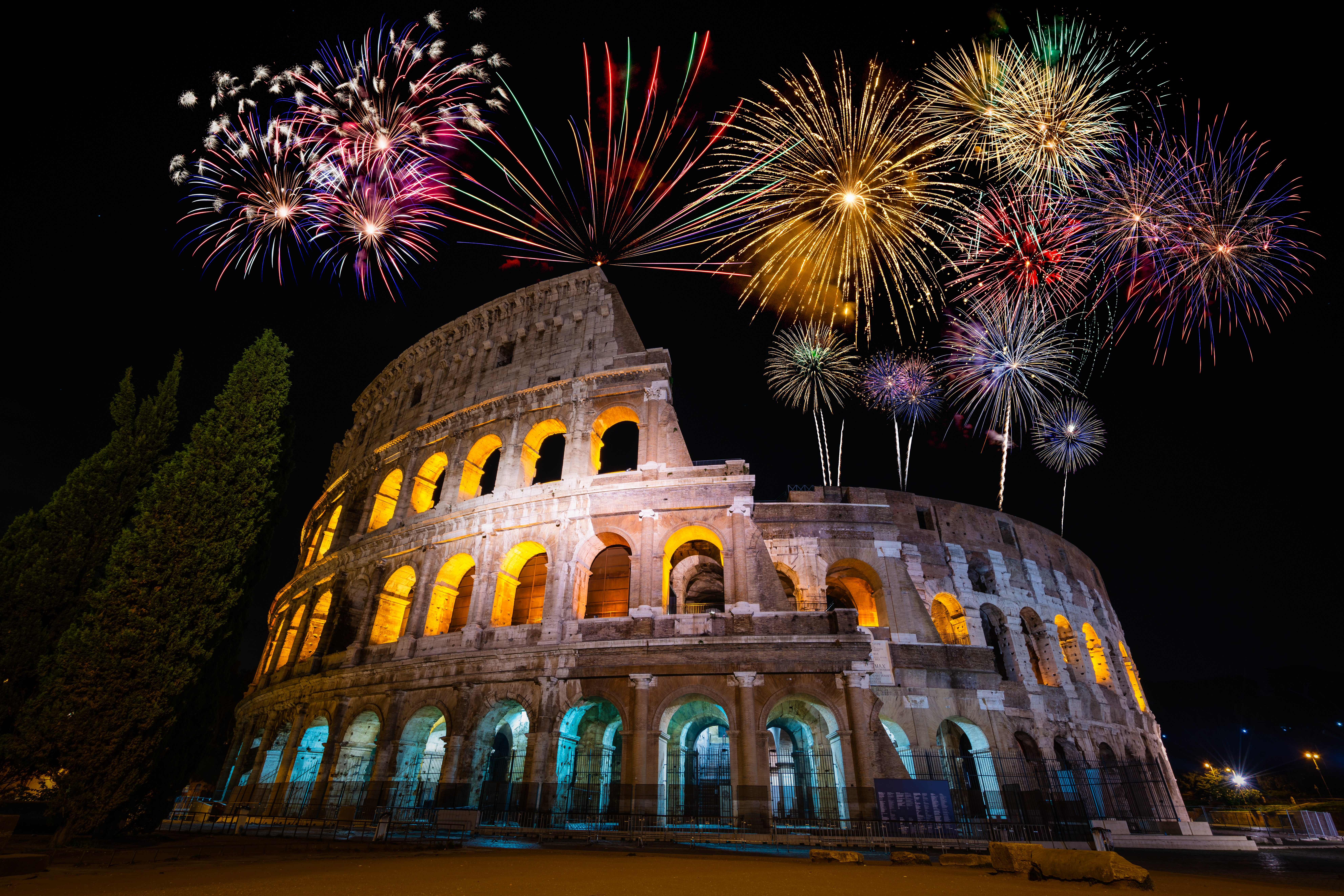 Oplyst Colosseum i Rom med eksplosivt nytårsfyrværkeri på den mørke nattehimmel i Italien