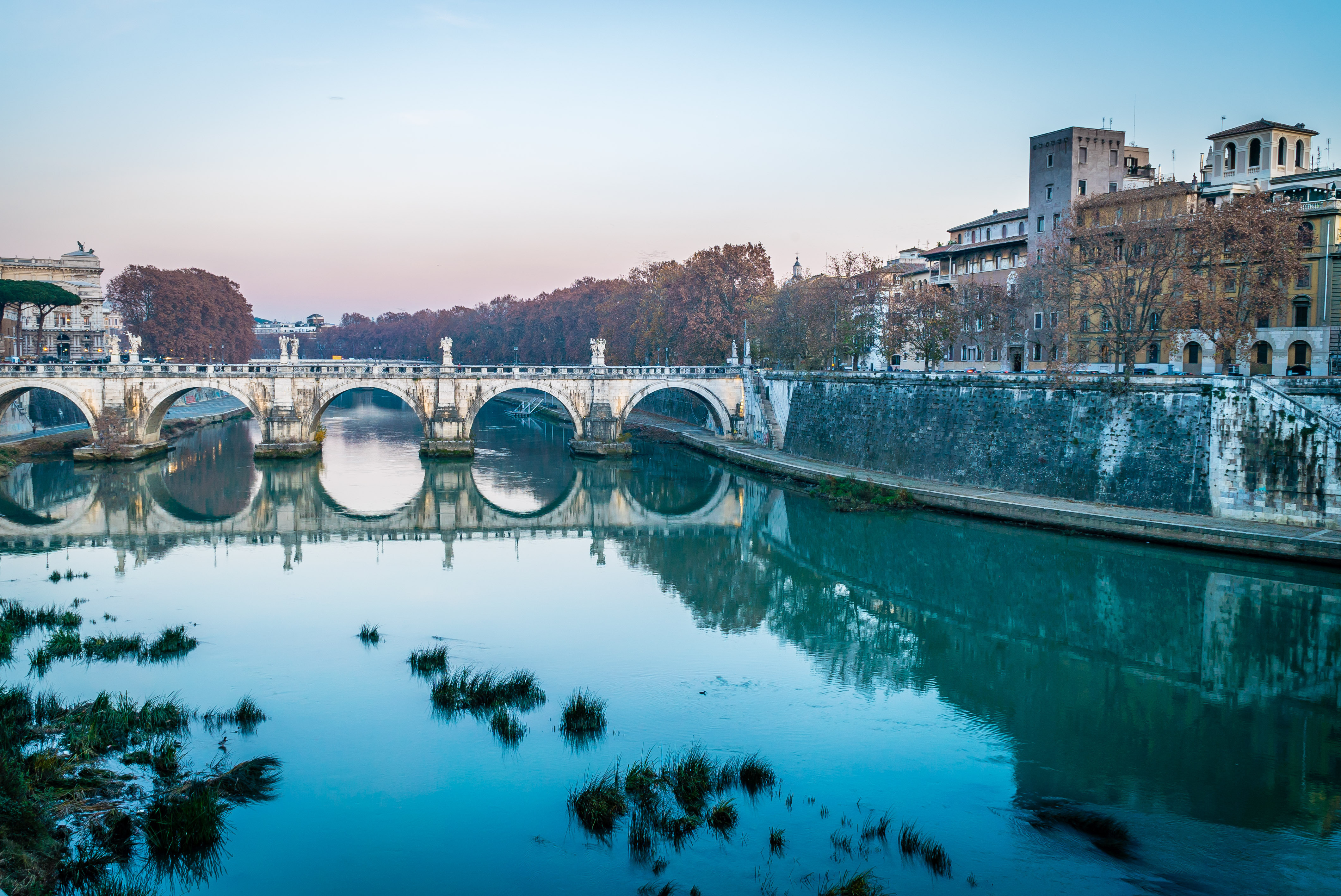 Ponte Sant'Angelo broen over Tiber-floden i Rom med smukt vinterlys og spejlinger i det stille vand