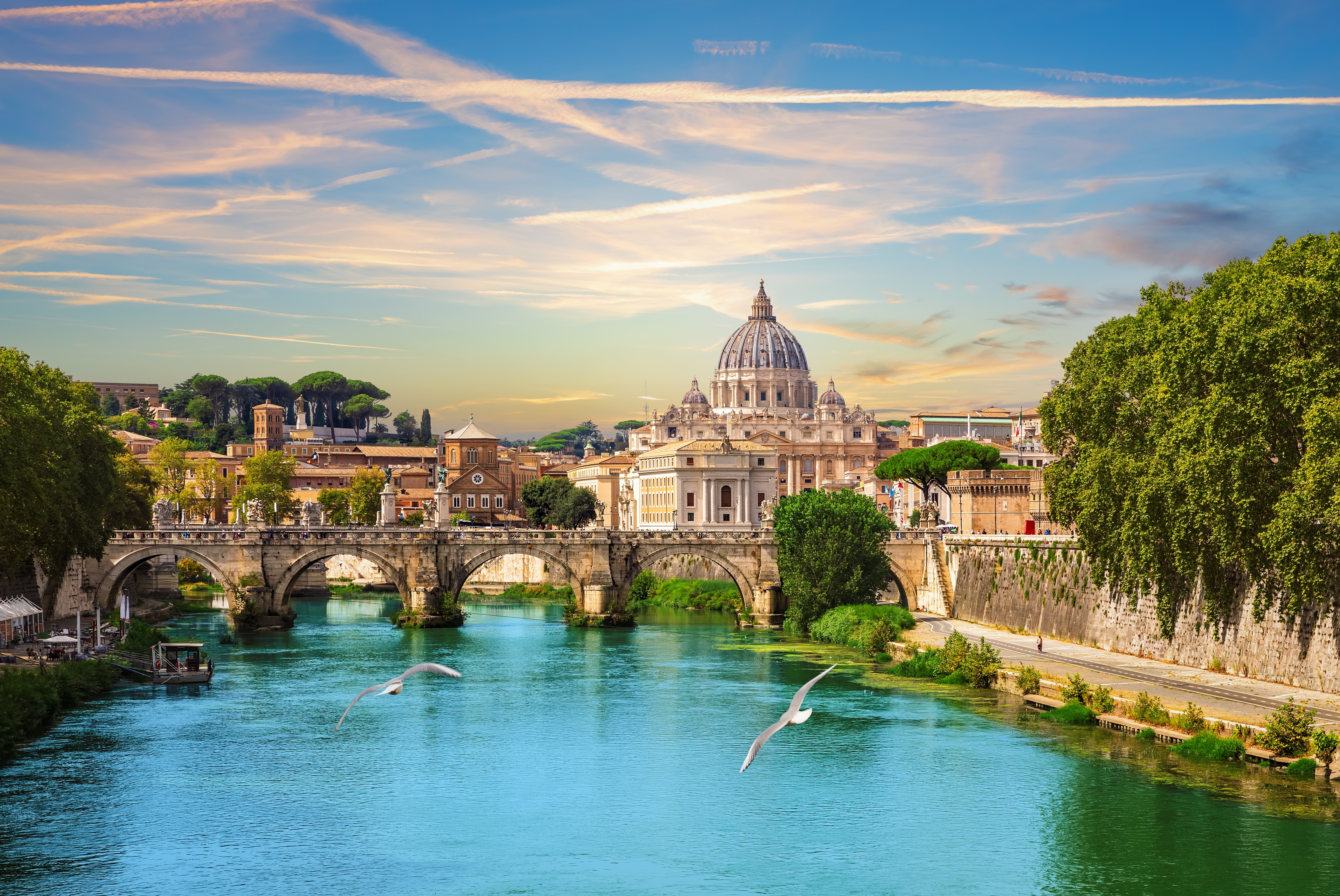Udsigt over Rom med den ikoniske Sankt Peters Basilika og Ponte Sant'Angelo bro spejlet i Tiberens turkisblå vand