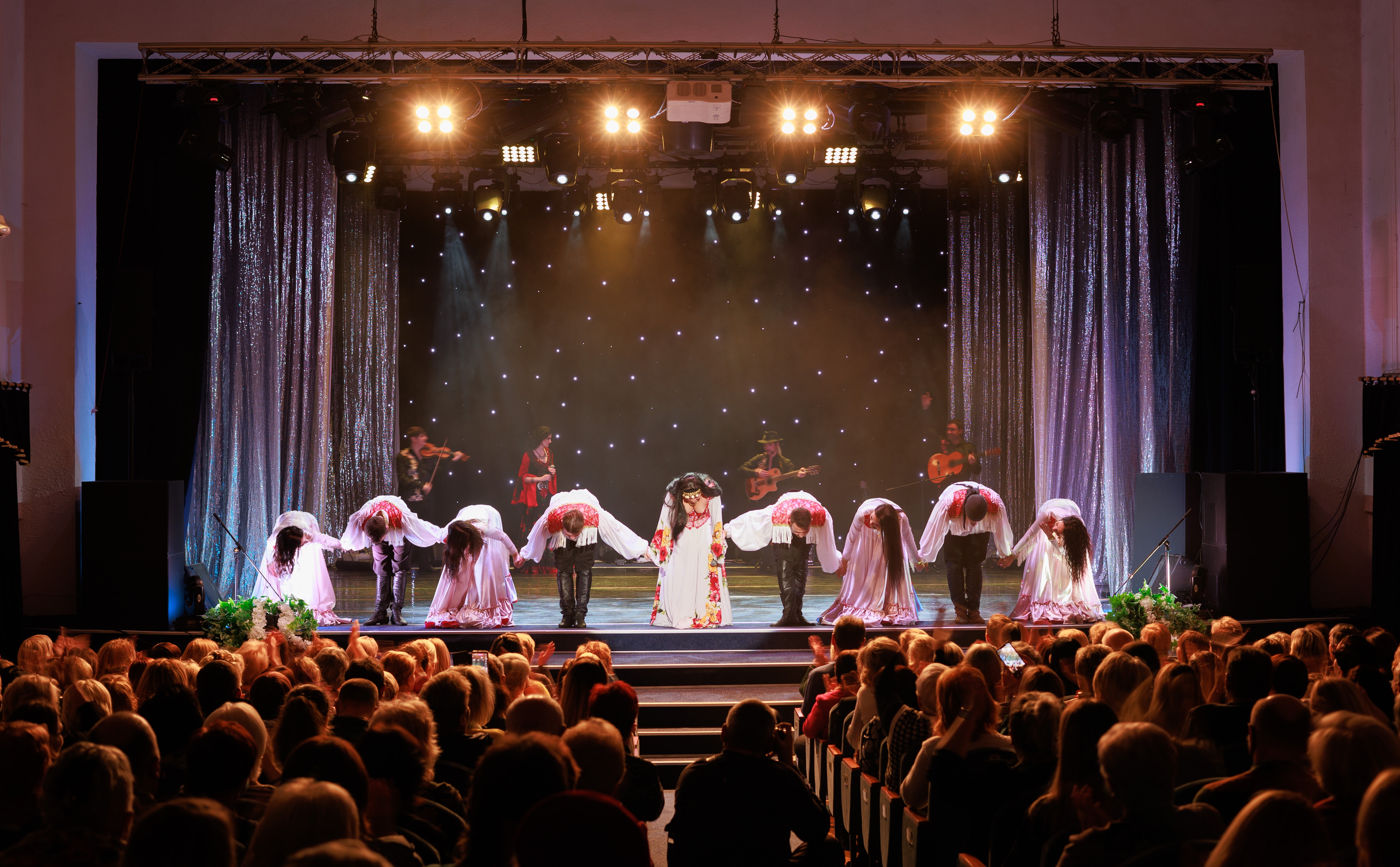 Romani dansere og musikere optræder i traditionelle kostumer under et kulturelt show på en festlig scene
