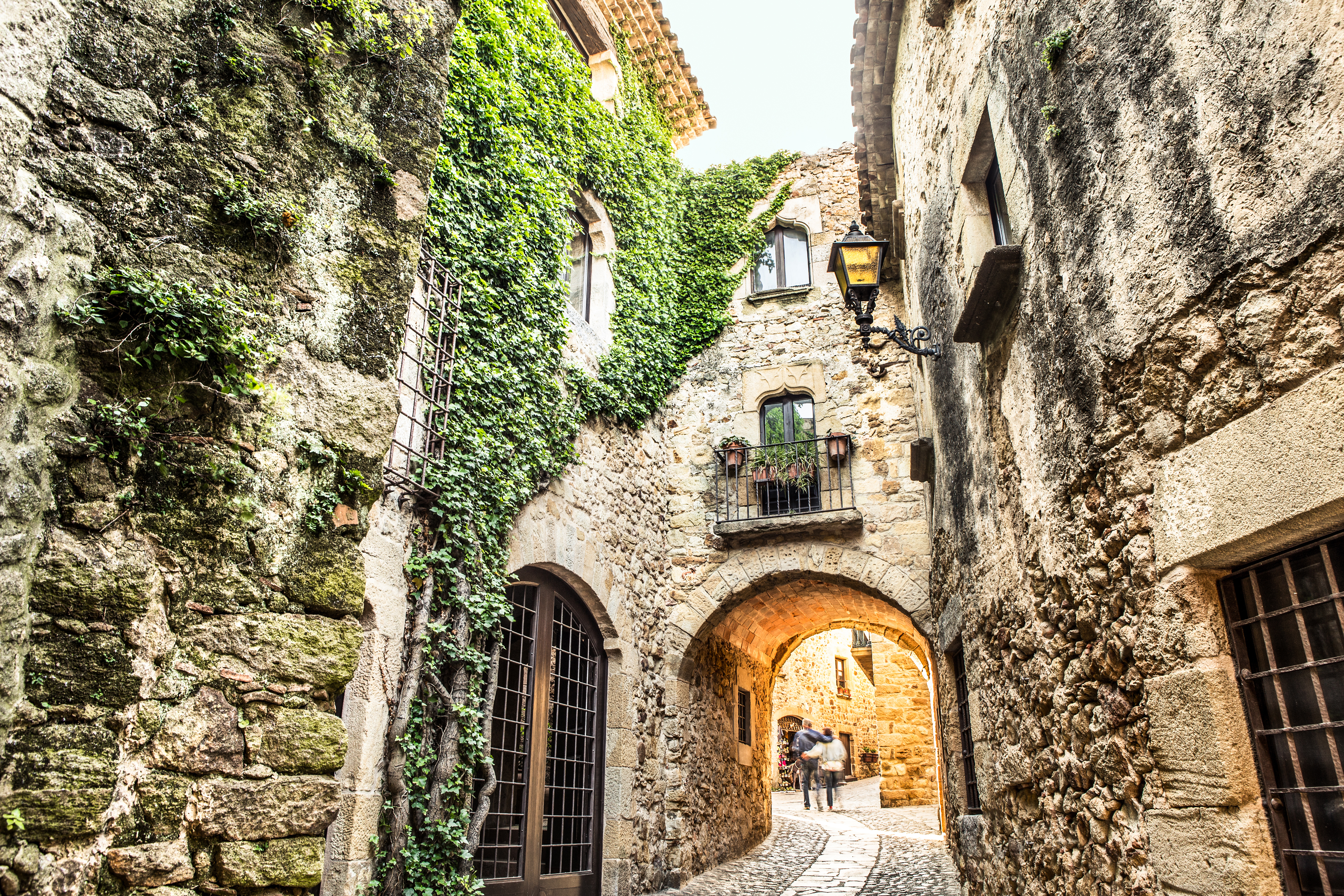 Romantisk stenport med efeu i middelalderlandsby i Girona-provinsen, Spanien