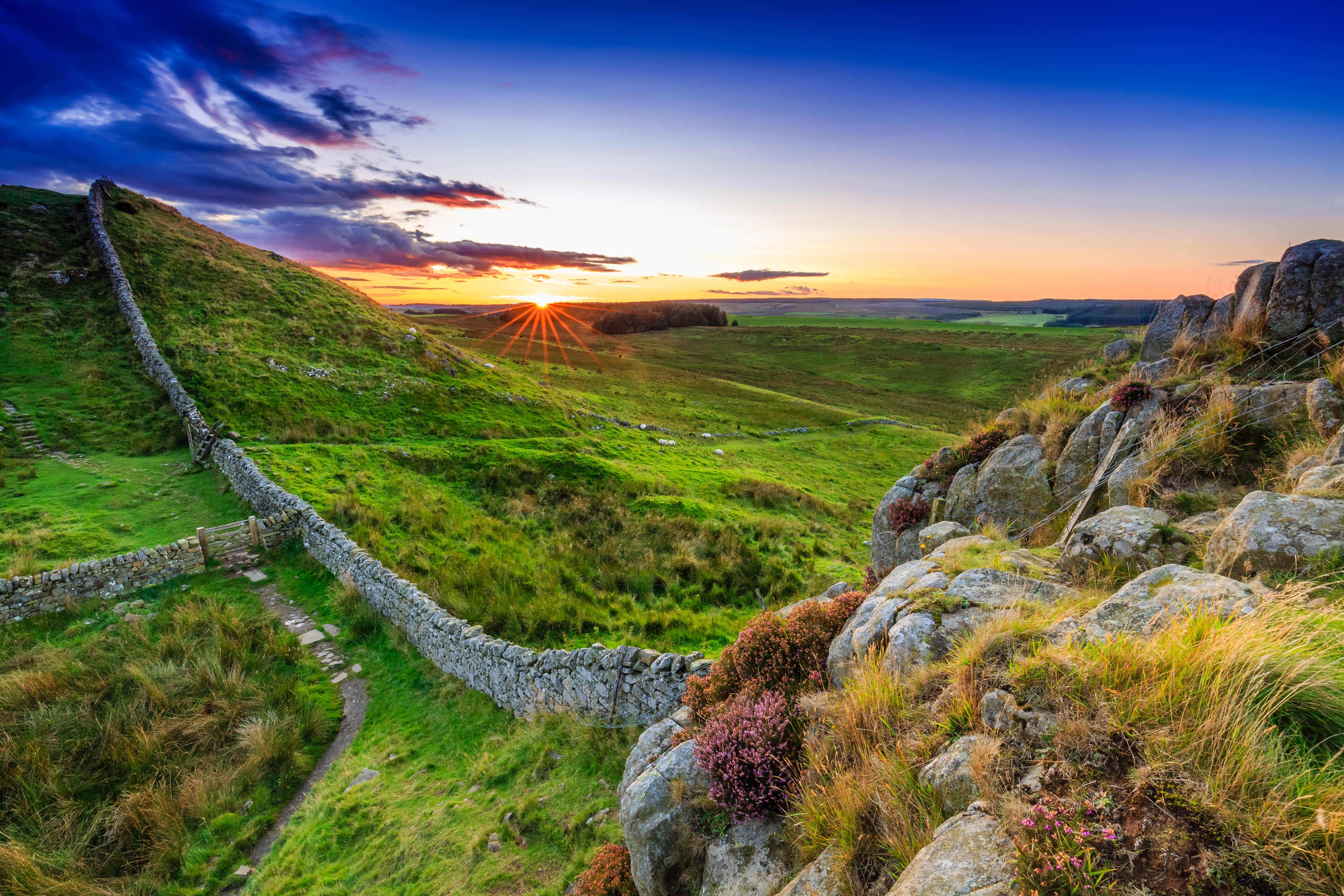 Historiske Hadrians Mur snoer sig gennem Northumberland ved solnedgang