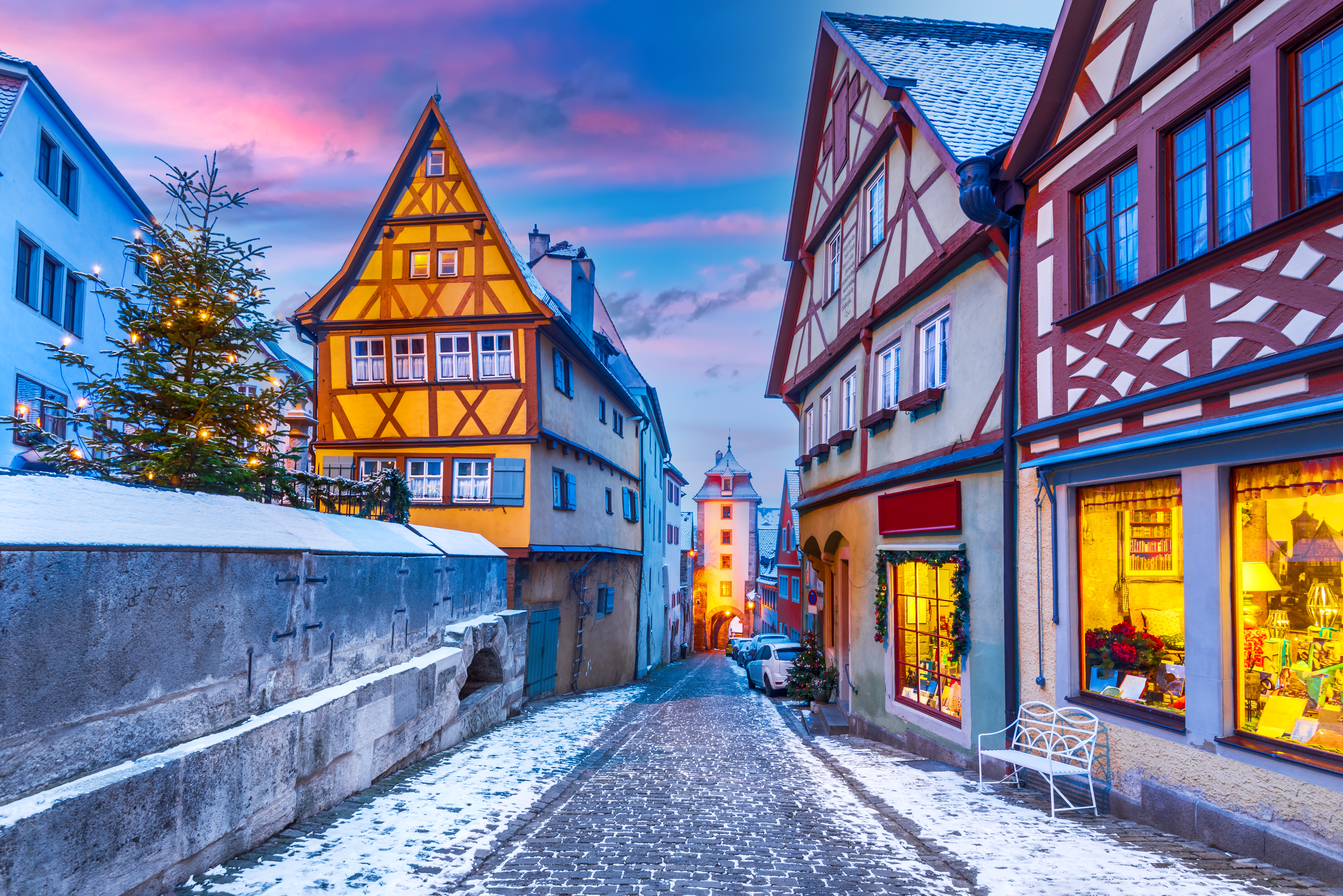 Magisk juleatmosfære i Rothenburg ob der Tauber med oplyste butiksvinduer og smukke bindingsværkshuse langs snedækkede gader