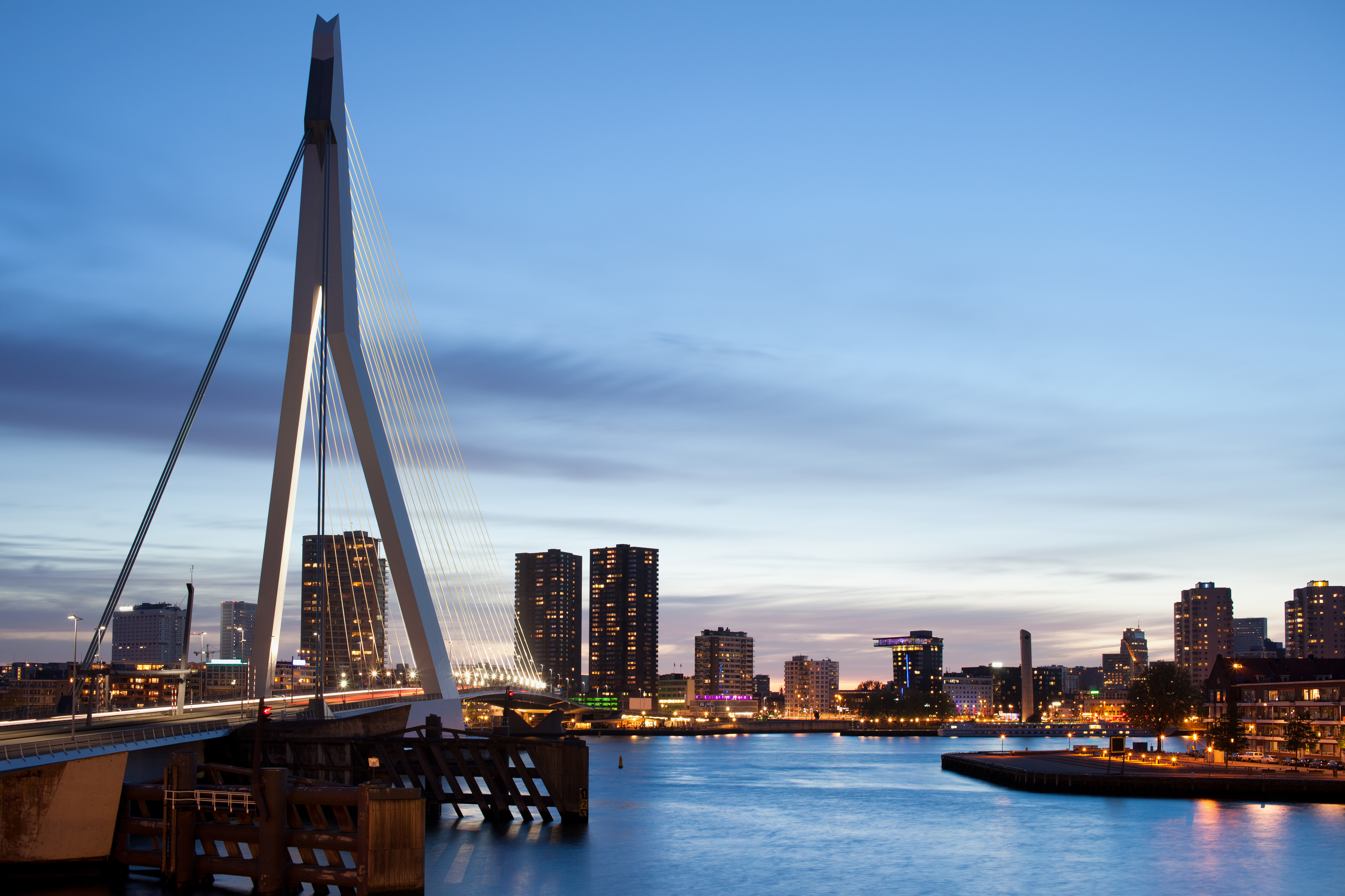 Rotterdam bys skyline ved solnedgang med den berømte Erasmus-bro og højhuse i baggrunden