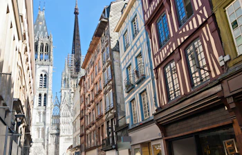 Stemningsfuld række af traditionelle franske bindingsværkshuse med synlige træbjælker og farverige facader i den historiske bykerne af Rouen, en af Normandiets mest charmerende byer