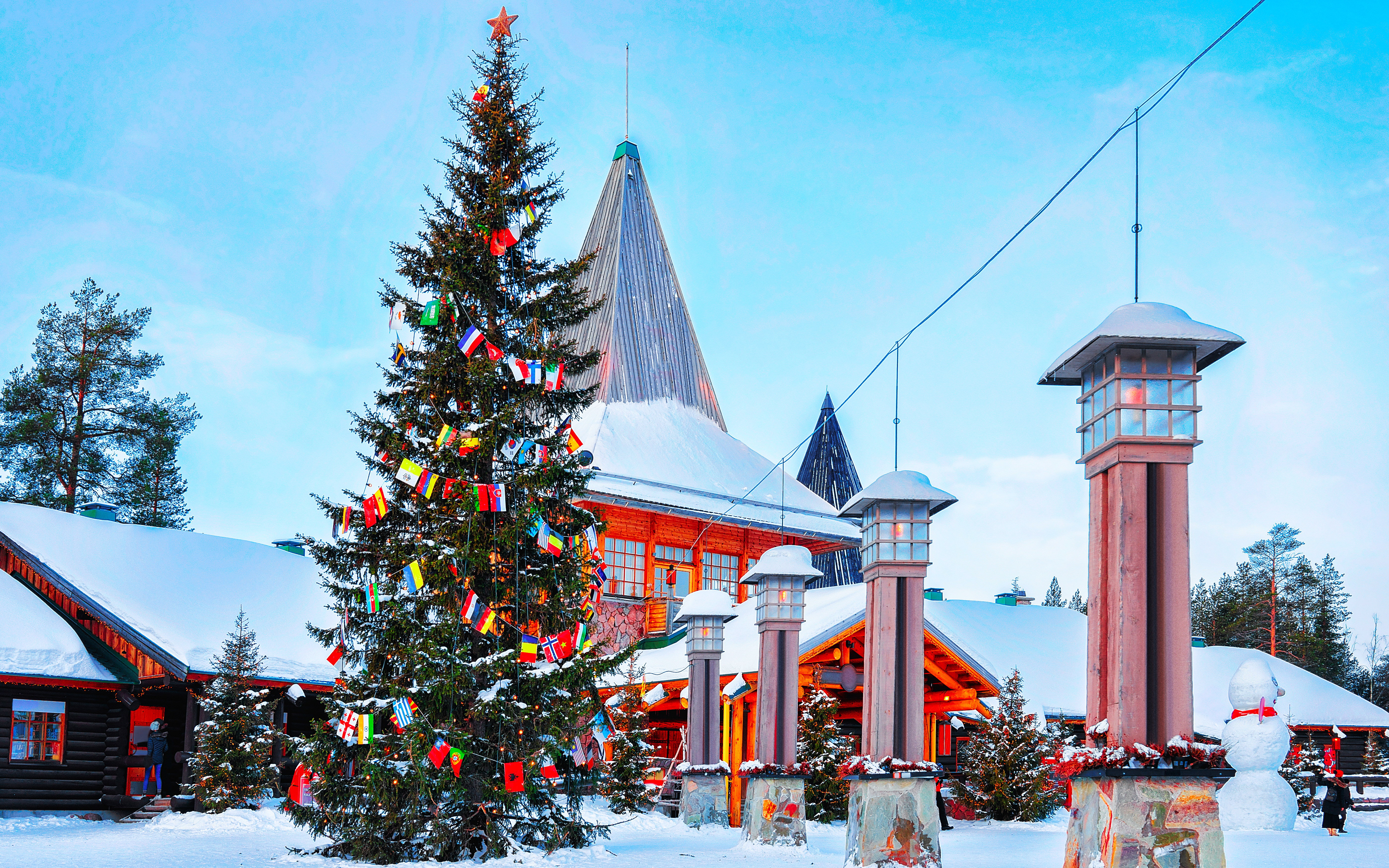 Julemandsbyen i Rovaniemi, Lapland med stort juletræ pyntet med flag fra hele verden, snedækkede huse og julestemning i det nordlige Finland