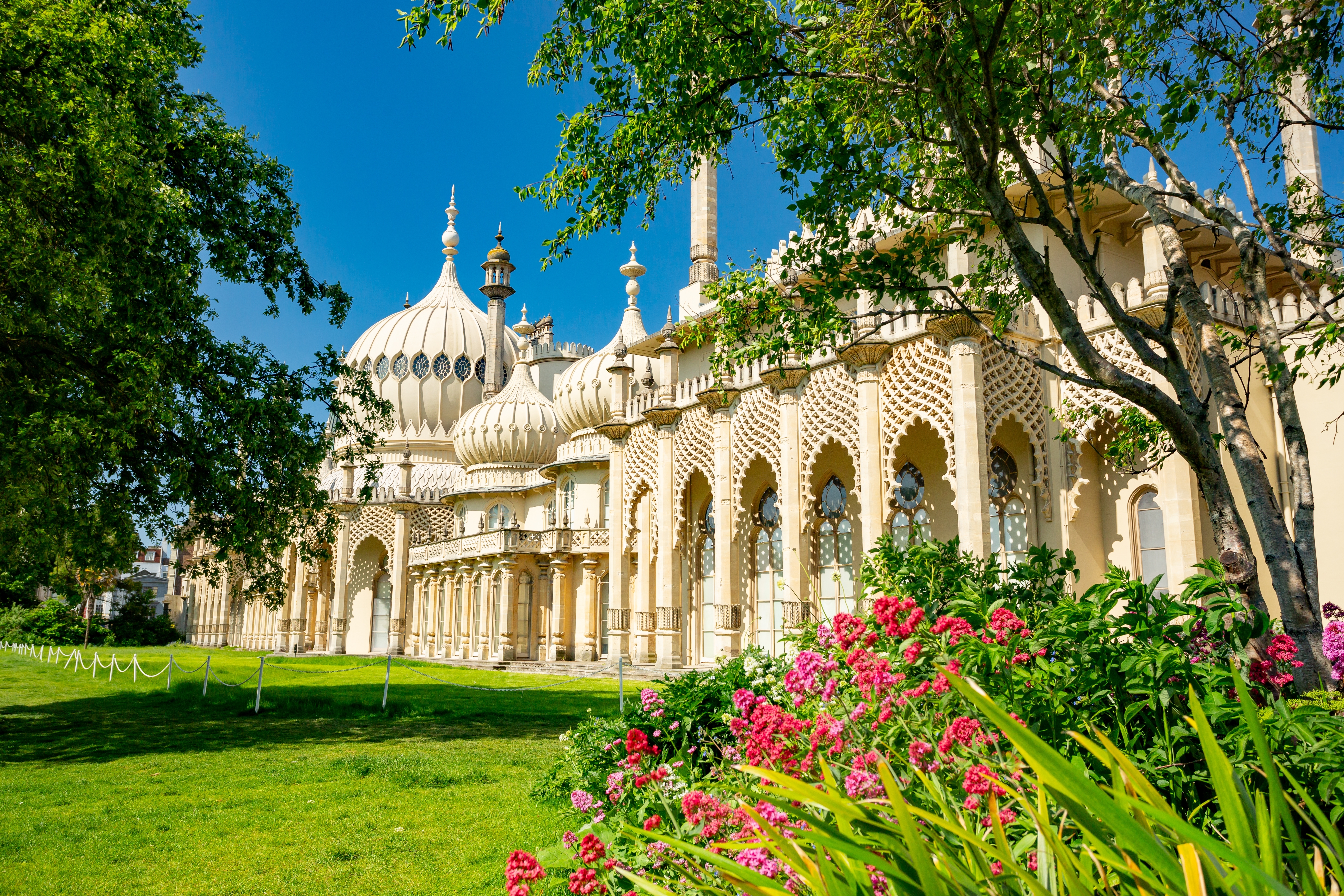 Det majestætiske Royal Pavilion i Brighton, Sussex, med karakteristiske hvide kupler og smuk have i strålende sommervejr