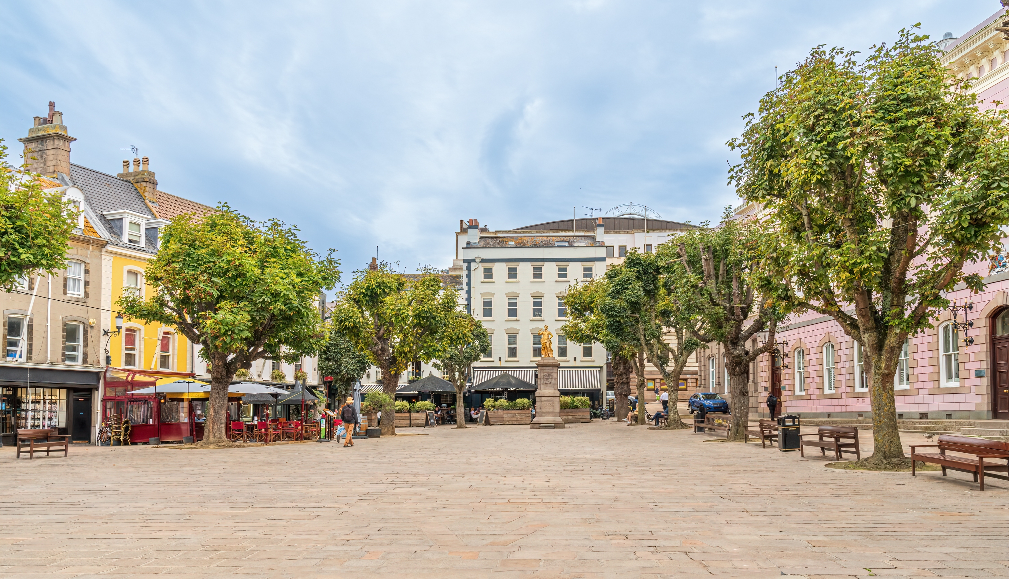 Idyllisk Royal Square på Jersey, Kanaløerne, med brolagte stier, grønne træer og hyggelige caféer